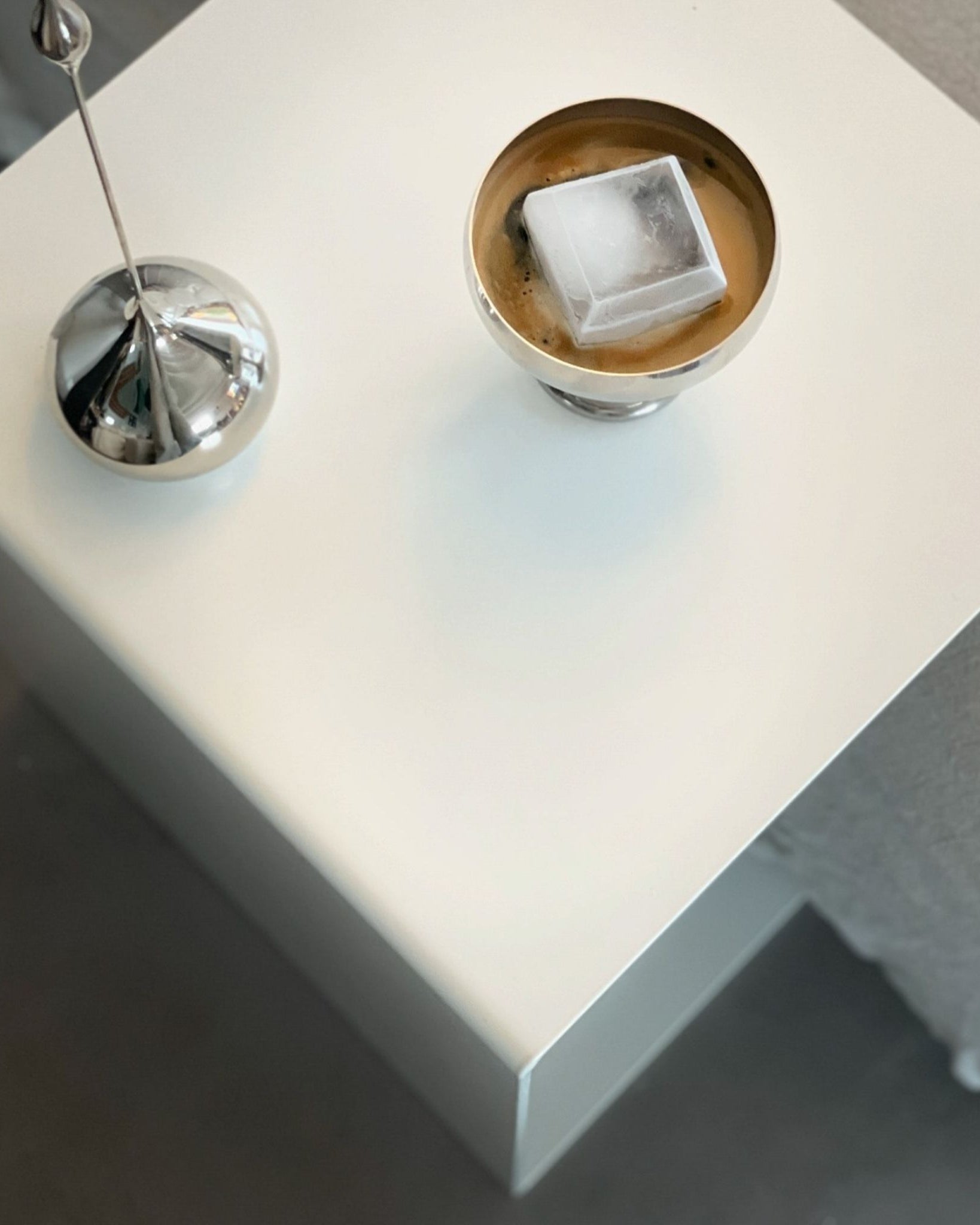 Weißer minimalistischer Beistelltisch mit Edelstahl-Dekoration und Kaffee