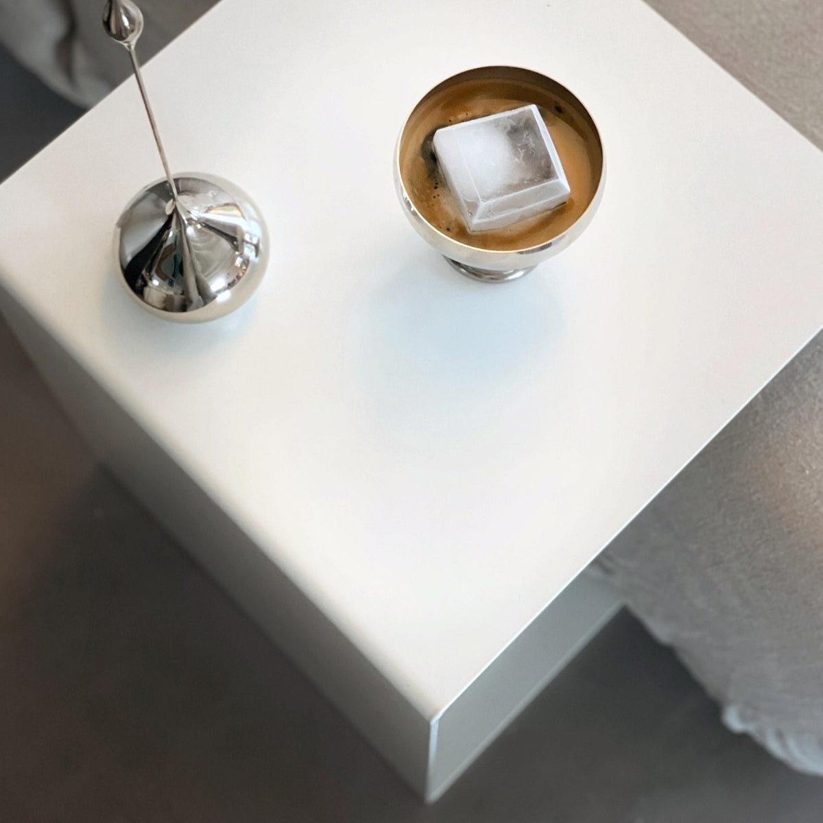 Weißer minimalistischer Beistelltisch mit Edelstahl-Dekoration und Kaffee