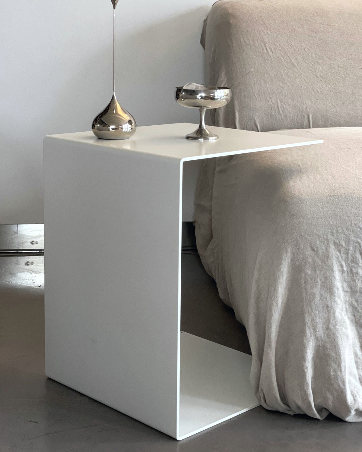 Minimalistischer weißer Beistelltisch neben einem Sofa mit Edelstahl-Deko