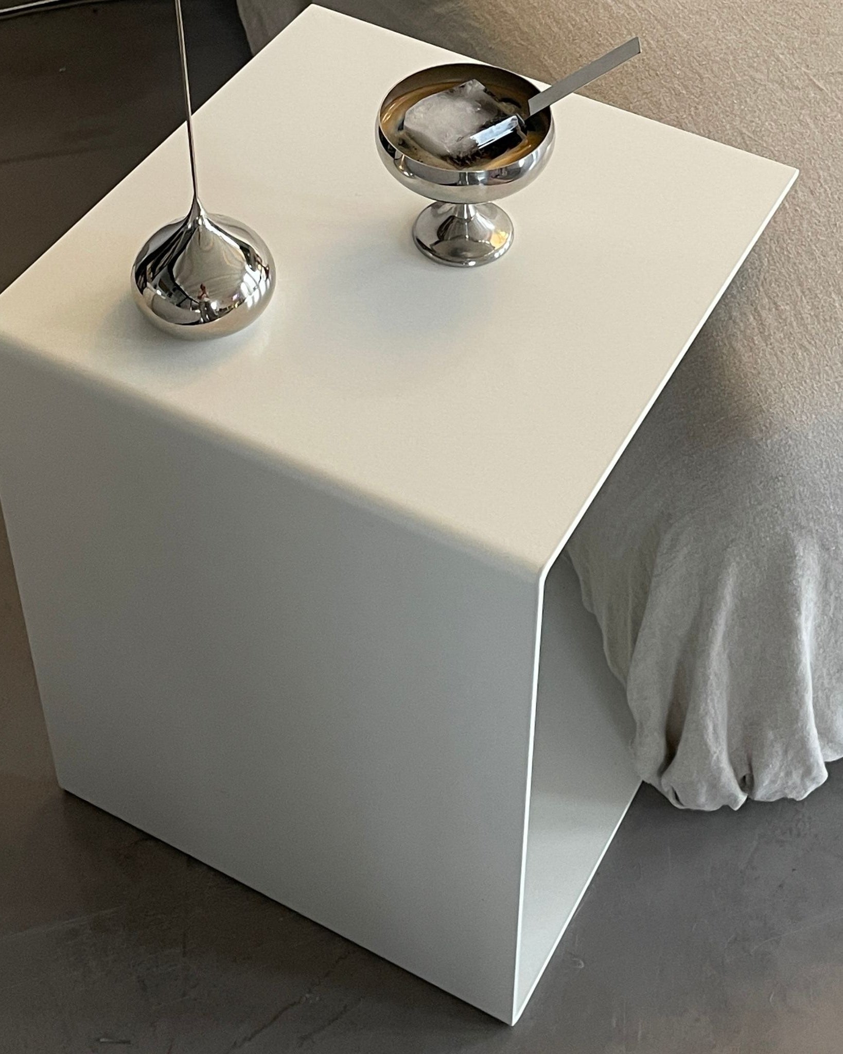 Moderner weißer Beistelltisch mit Edelstahl-Dekoration neben einem Sofa