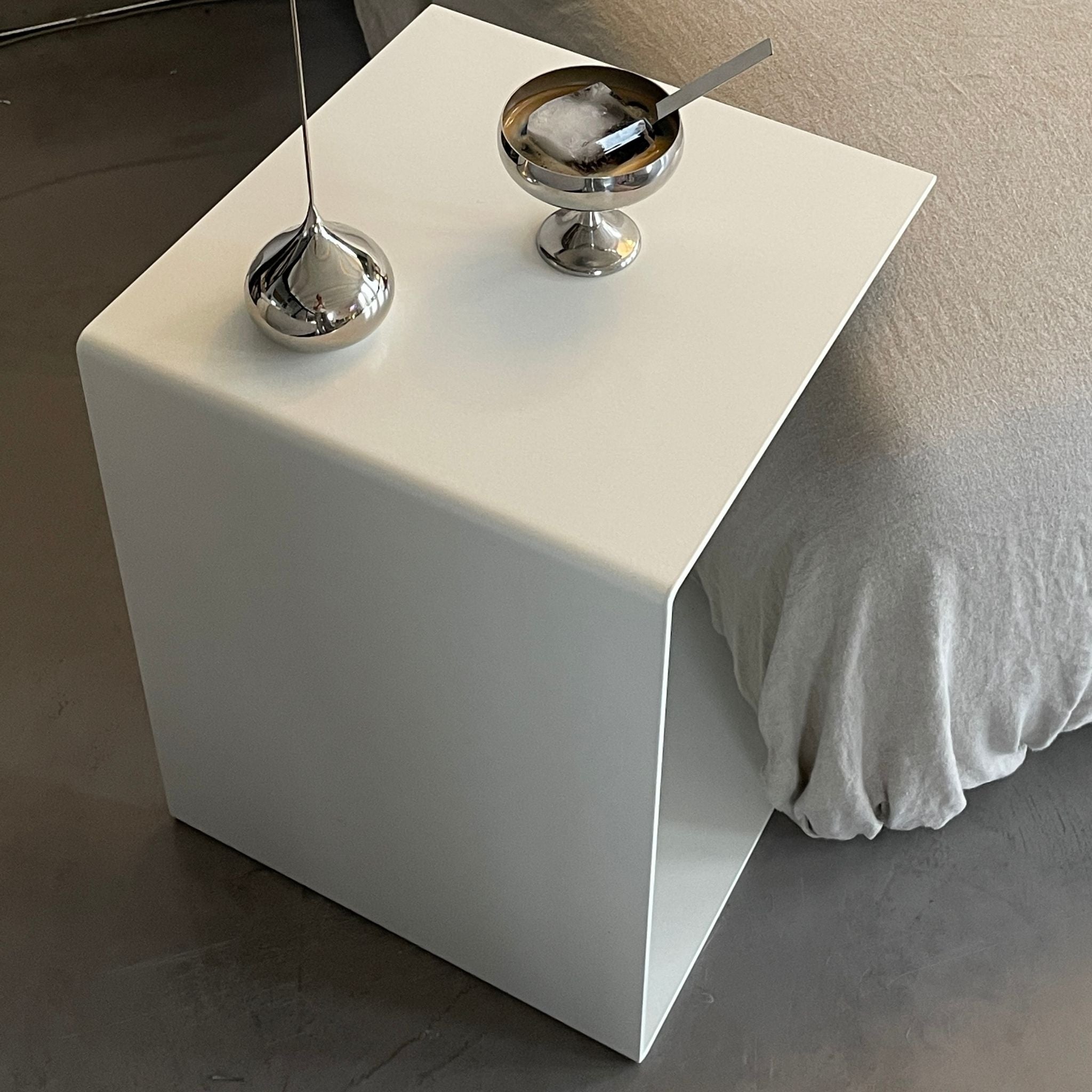 Moderner weißer Beistelltisch mit Edelstahl-Dekoration neben einem Sofa