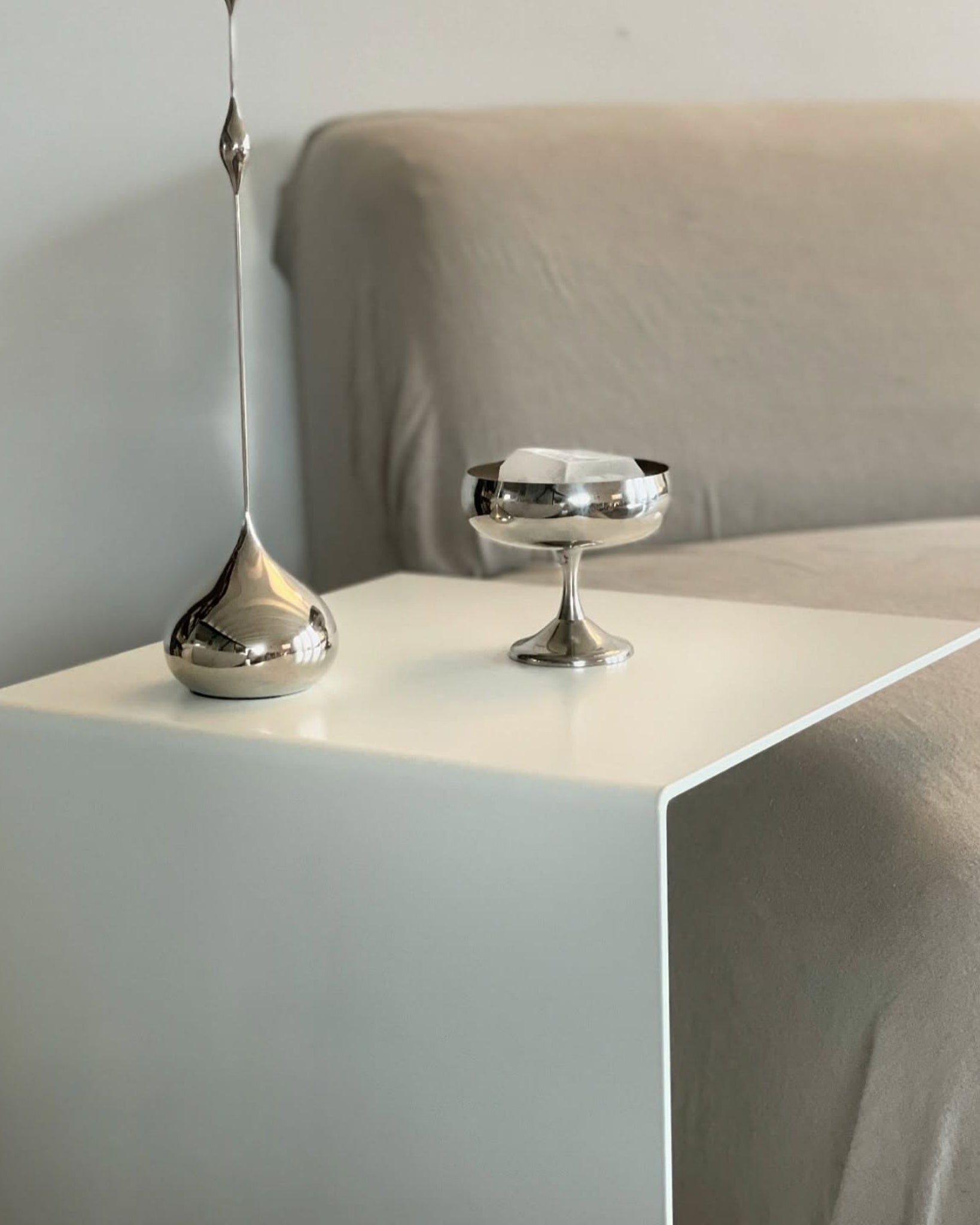 Minimalistischer Beistelltisch in Weiß mit Edelstahl-Dekoration am Sofa