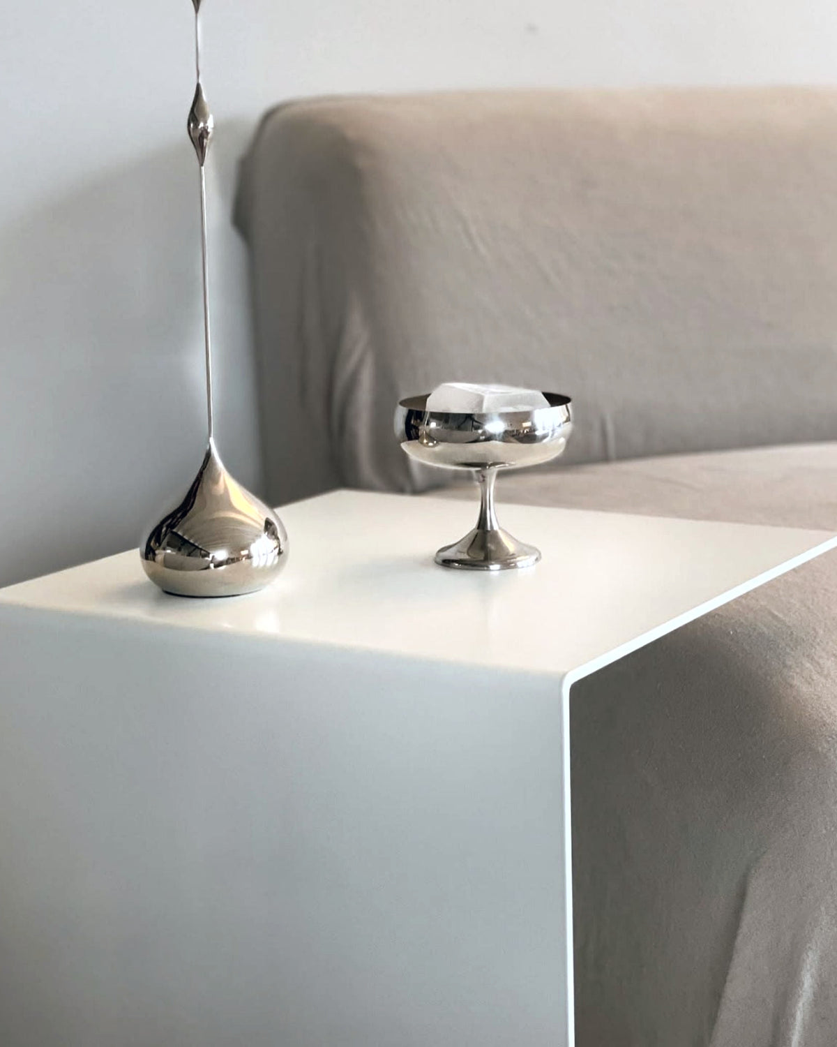Minimalistischer Beistelltisch in Weiß mit Edelstahl-Dekoration am Sofa