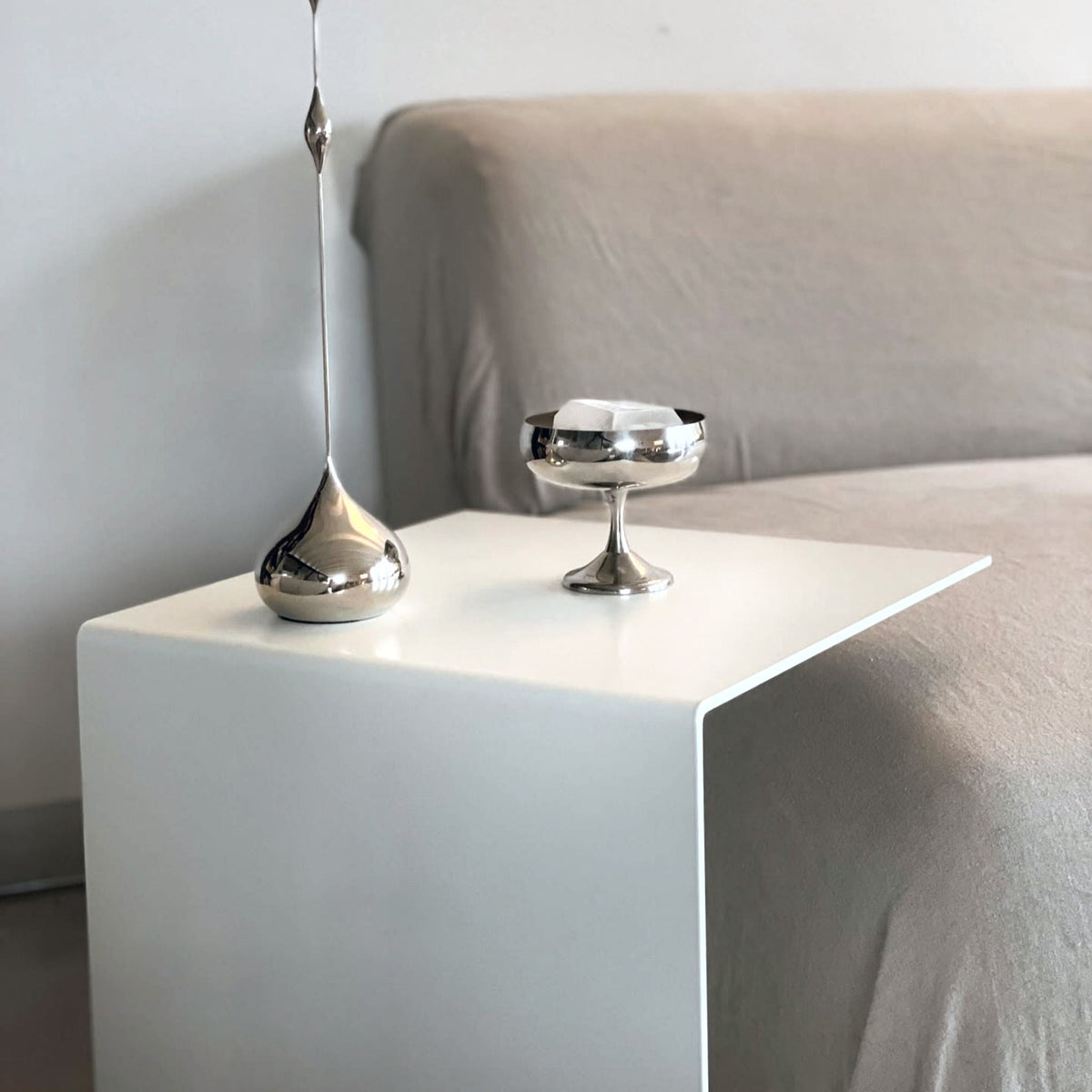 Minimalistischer Beistelltisch in Weiß mit Edelstahl-Dekoration am Sofa