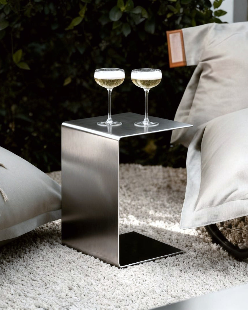 Brushed C Beistelltisch aus gebürstetem Edelstahl im Outdoor Lounge Setting mit zwei Champagnergläsern