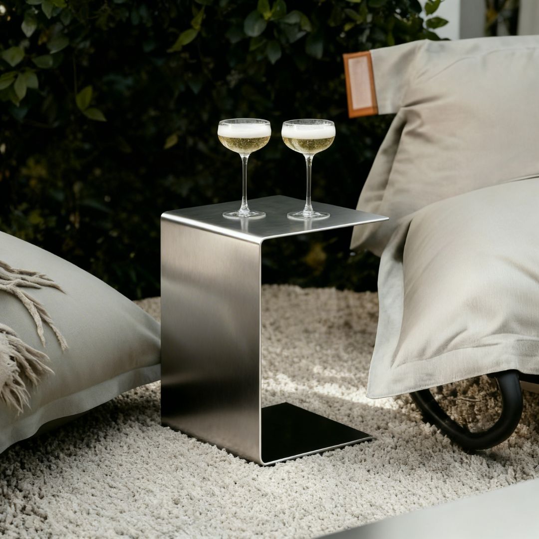 Brushed C Beistelltisch aus gebürstetem Edelstahl im Outdoor Lounge Setting mit zwei Champagnergläsern