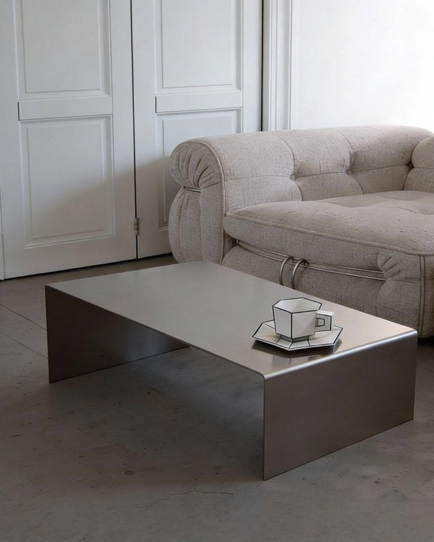 Brushed C Long Couchtisch aus gebürstetem Edelstahl im Wohnzimmer vor Sofa mit ruhiger, minimalistischer Raumwirkung