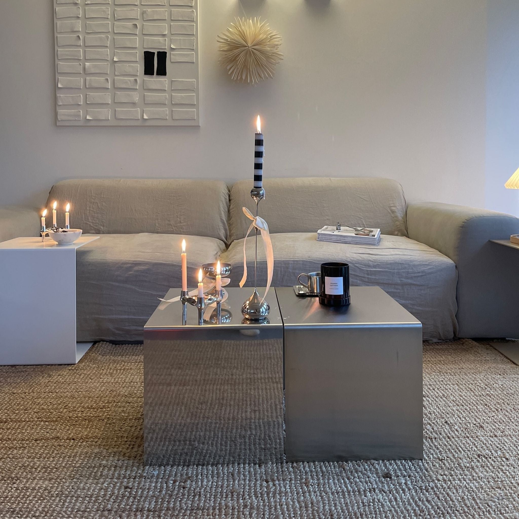 Moderner Couchtisch aus Edelstahl, spiegelpoliert und gebürstet, stilvoll dekoriert mit Kerzen und Accessoires