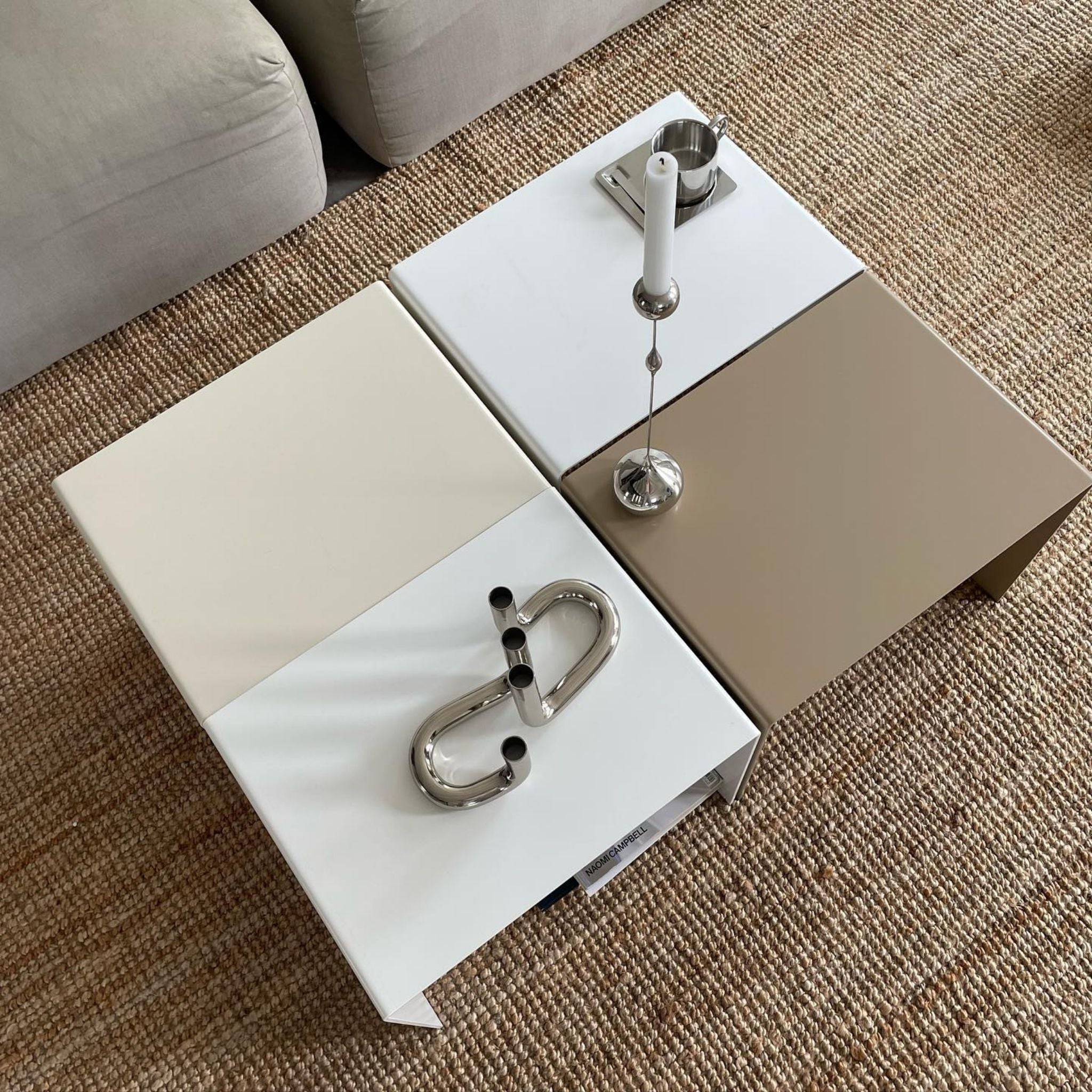 Vier Couchtische in verschiedenen Farben kombiniert zu einem großen Tisch, dekoriert mit Edelstahl-Accessoires