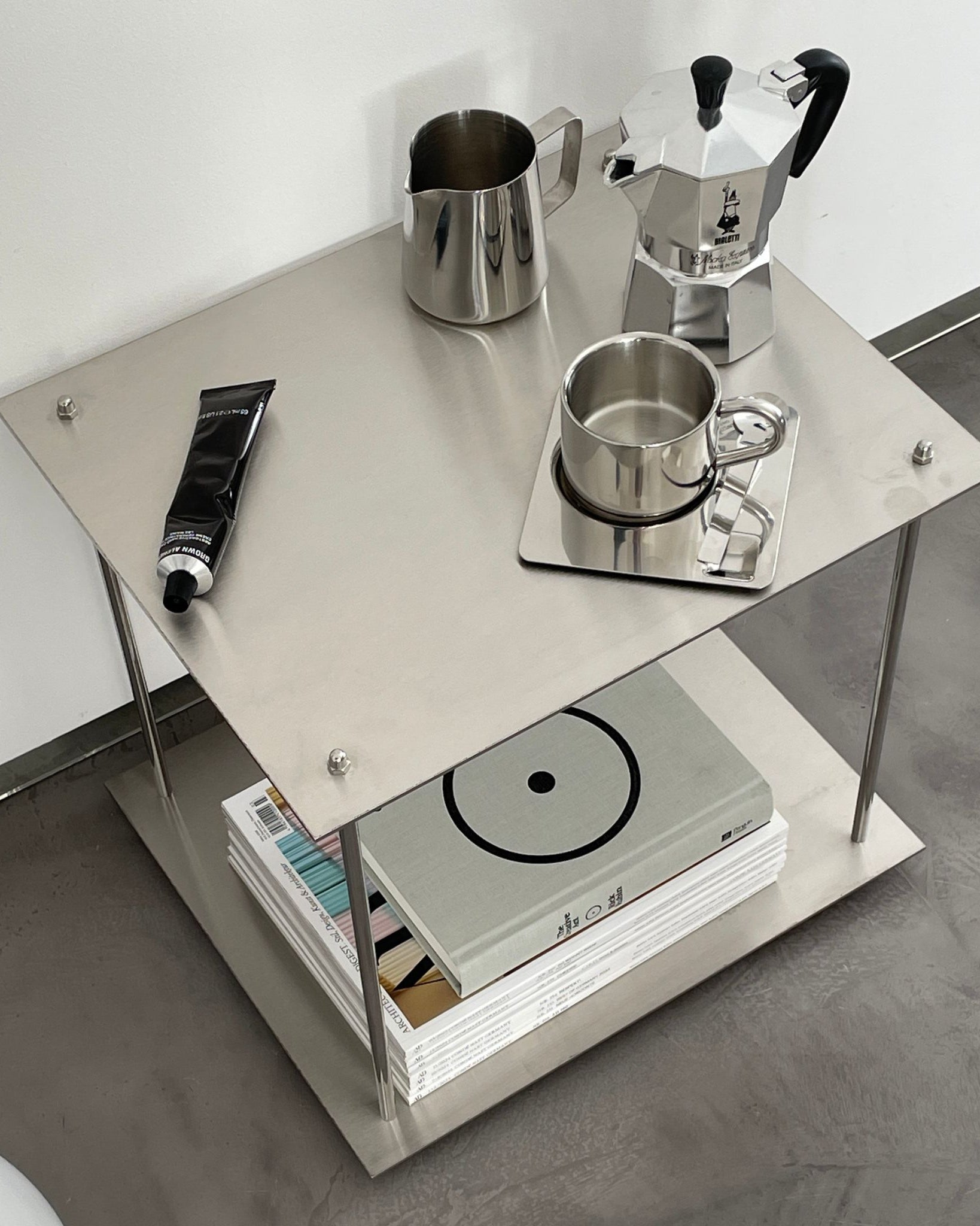 Modernes Edelstahl-Regal mit Espressokanne, Milchkännchen und Designmagazinen