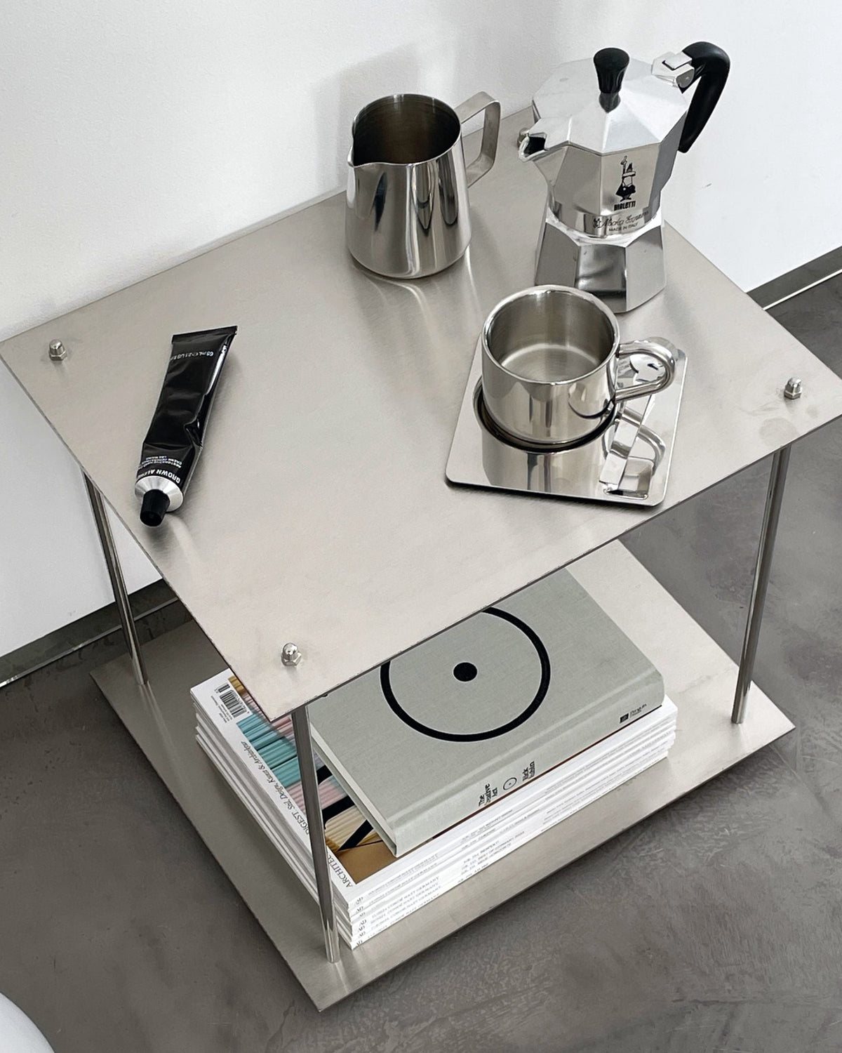 Modernes Edelstahl-Regal mit Espressokanne, Milchkännchen und Designmagazinen