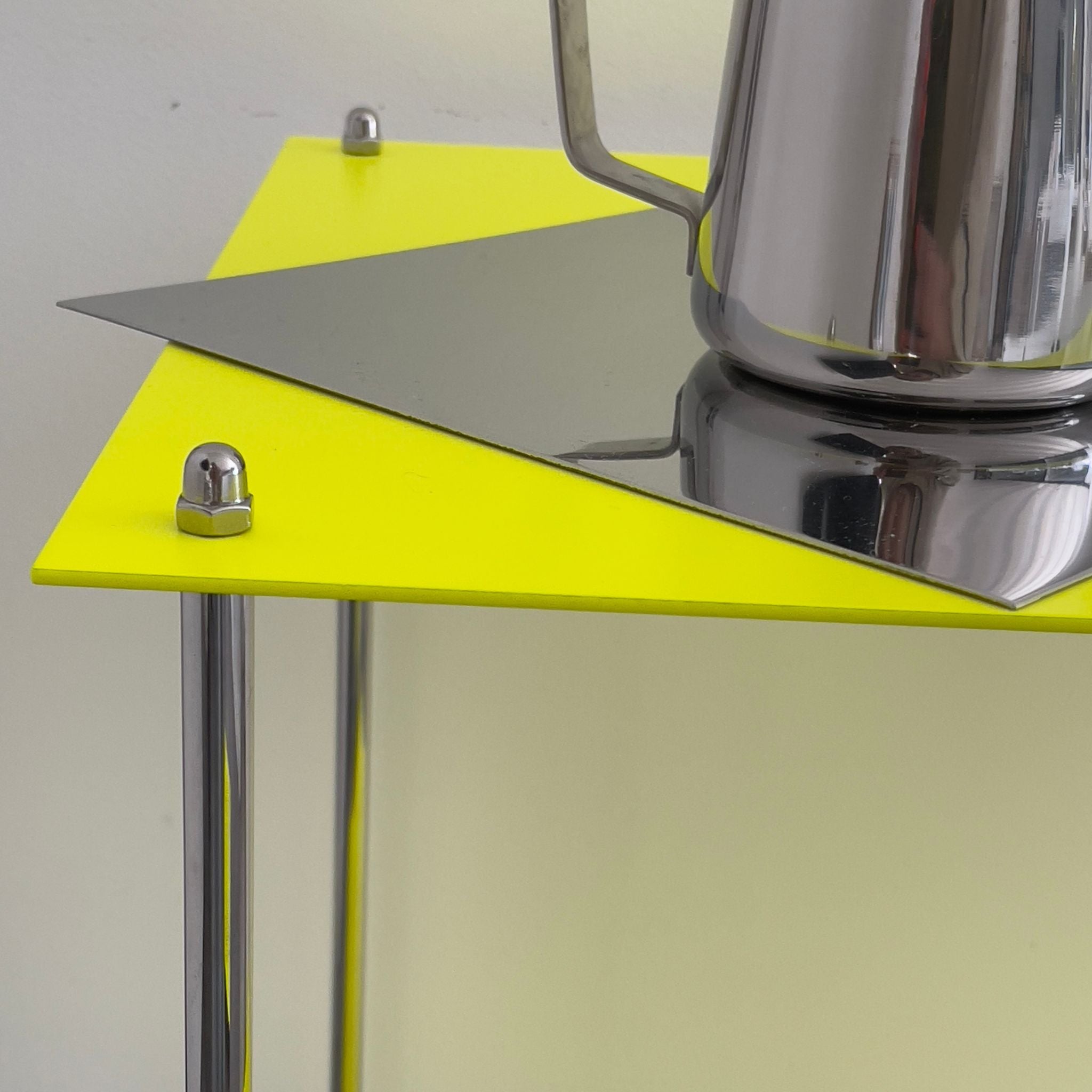 Detailansicht MODULUM Regal in Leuchtgelb mit Edelstahlverschraubung und glänzender Kanne auf Spiegelfläche