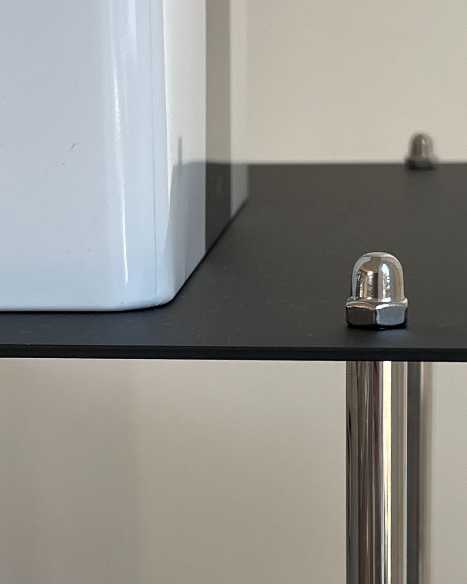 Detailansicht schwarzer Regalboden mit Edelstahlmutter und pulverbeschichteter Oberfläche