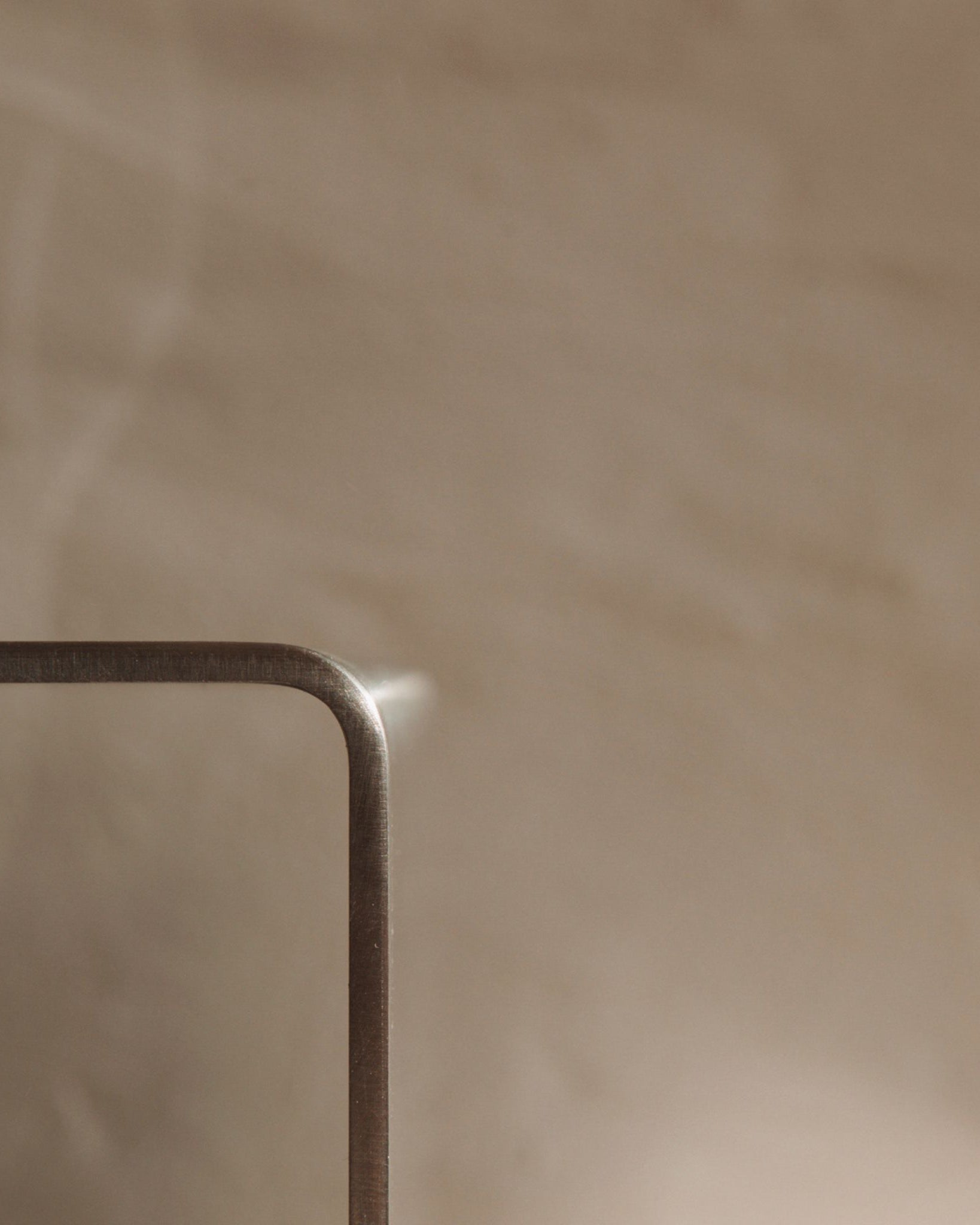 Detailaufnahme einer gebogenen Edelstahlkante mit sanfter Lichtreflexion