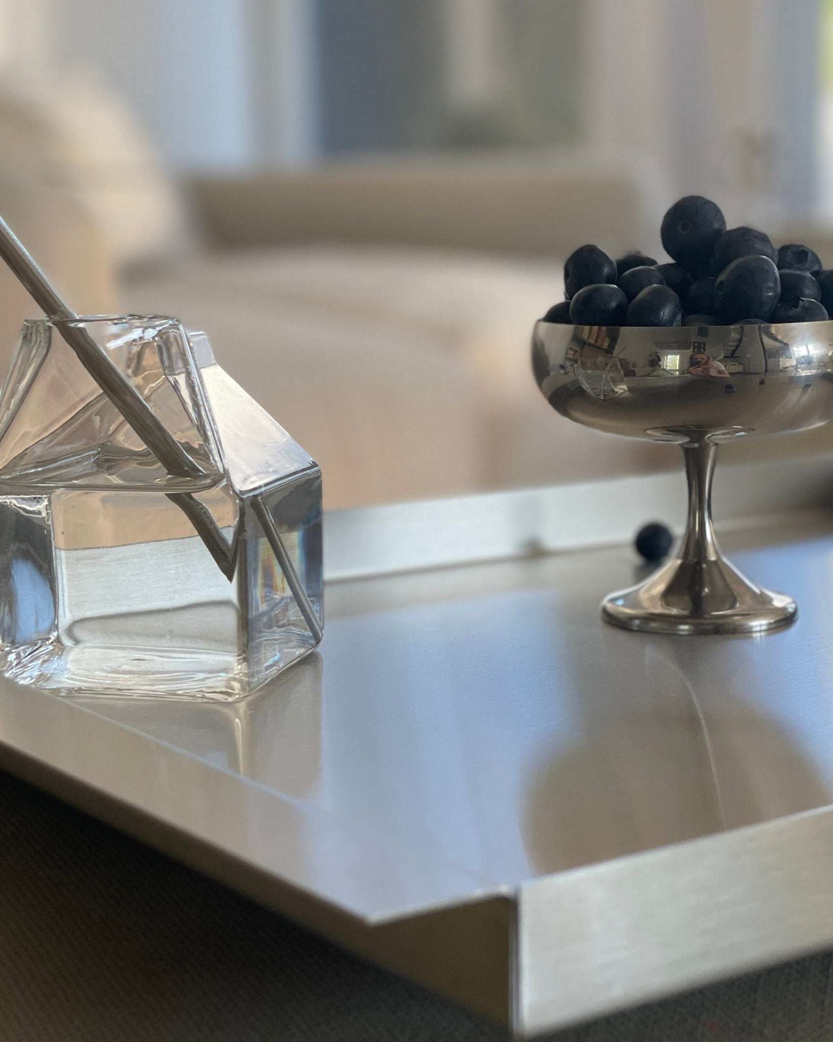 edelstahl tablett mit glassstrohhalm und blaubeeren auf stoffsofa
