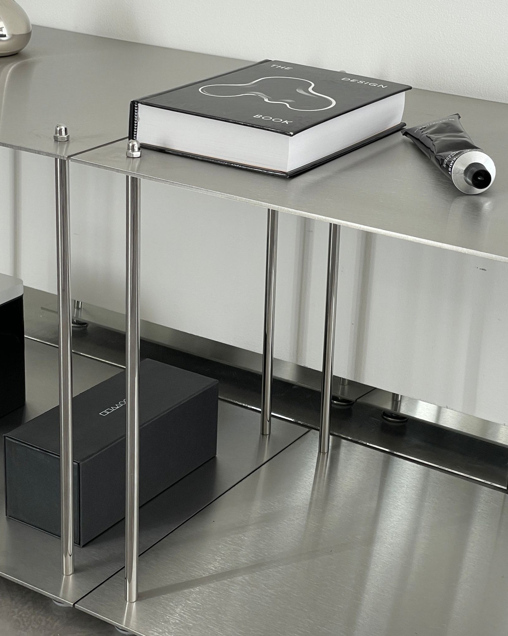 Minimalistisches Lowboard aus Edelstahl mit Design-Accessoires und Bücherablage