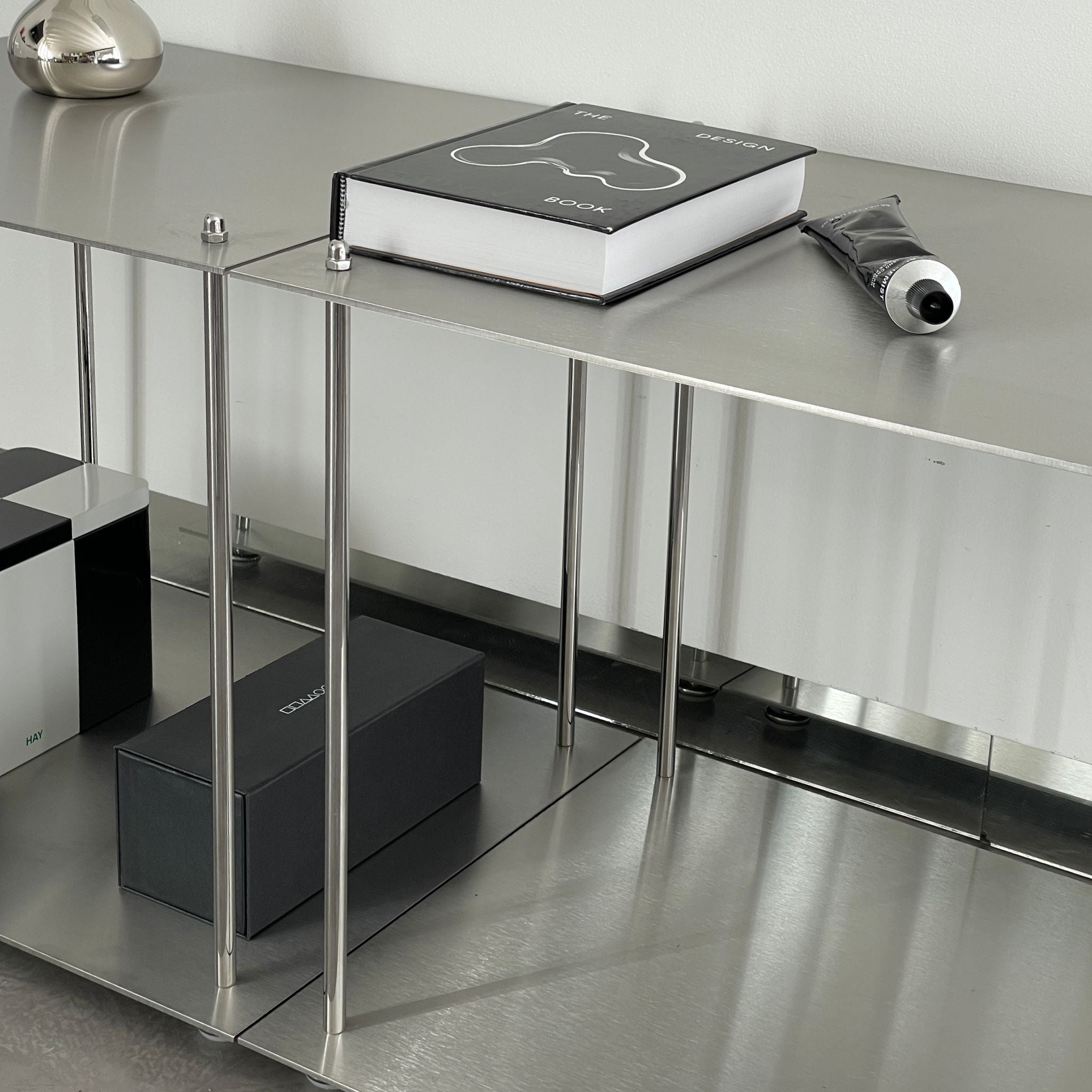 Minimalistisches Lowboard aus Edelstahl mit Design-Accessoires und Bücherablage