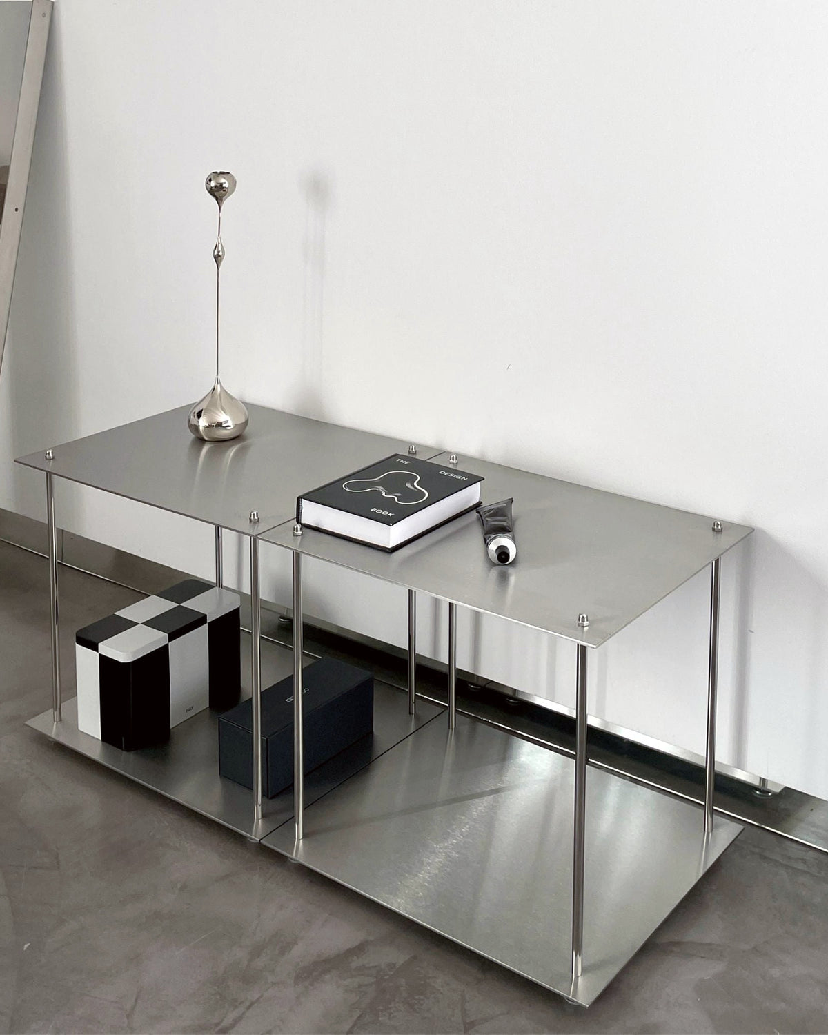 Modulares Lowboard aus Edelstahl mit Designobjekten und Aufbewahrungsboxen in minimalistischem Wohnraum