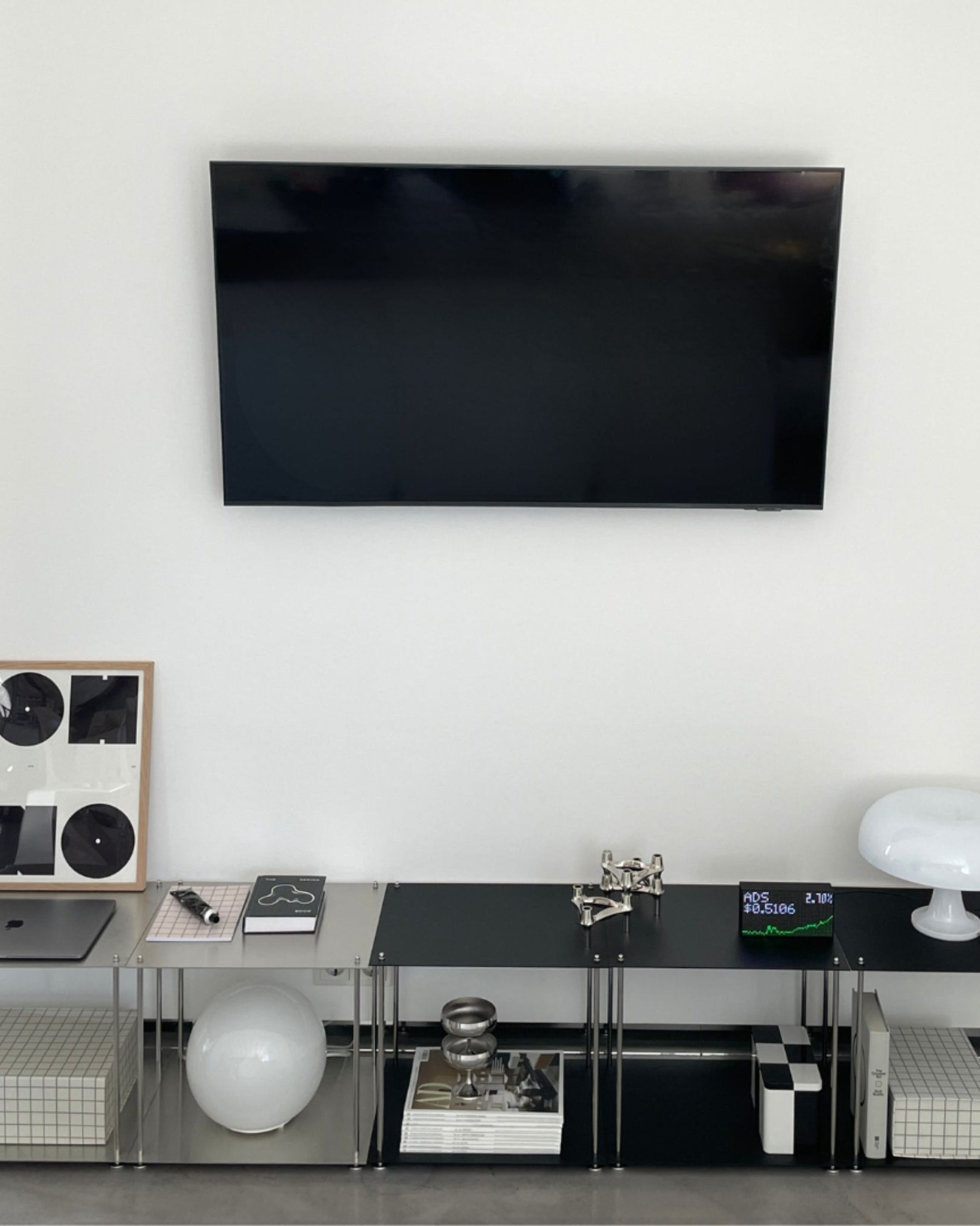 Modulares Lowboard aus Edelstahl in Schwarz mit TV und Designobjekten im minimalistischen Wohnzimmer