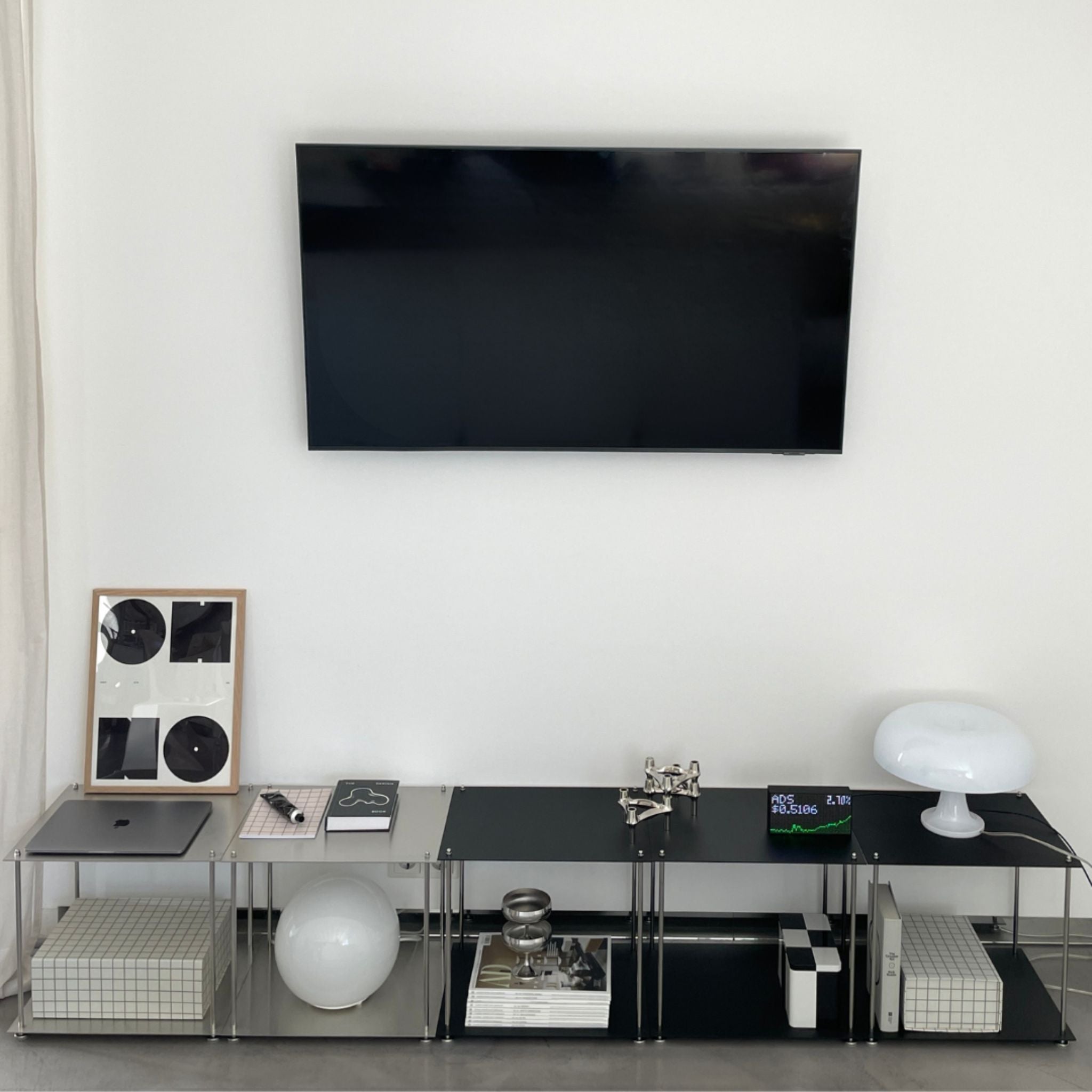 Modulares Lowboard aus Edelstahl in Schwarz mit TV und Designobjekten im minimalistischen Wohnzimmer
