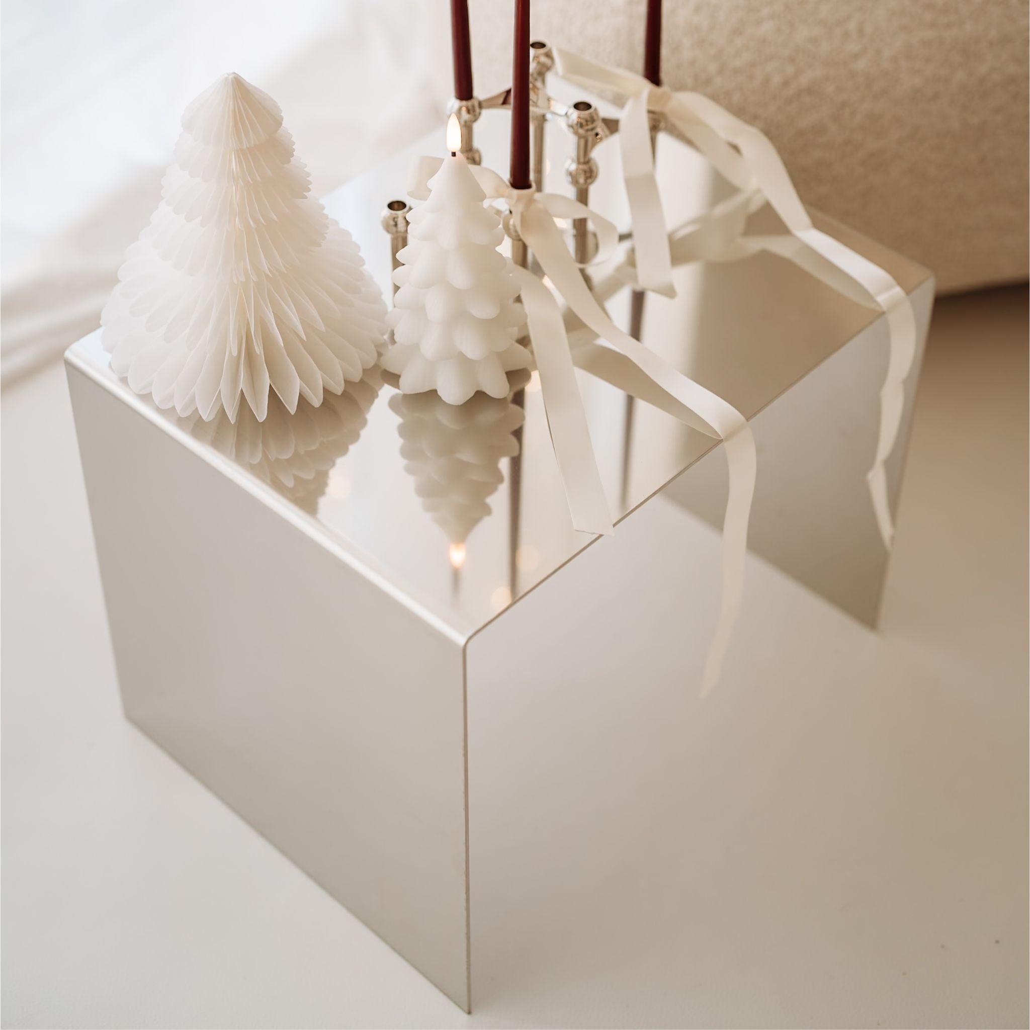 Detail des Mirror C Beistelltischs aus poliertem Edelstahl mit weißen Weihnachtskerzen und Deko im hellen Wohnzimmer