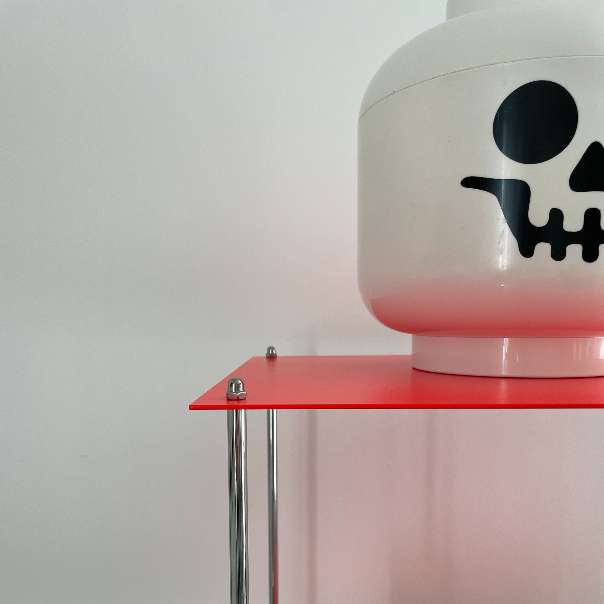 Leuchtrotes Regal mit weißem Lego-Kopf mit Totenkopf-Gesicht
