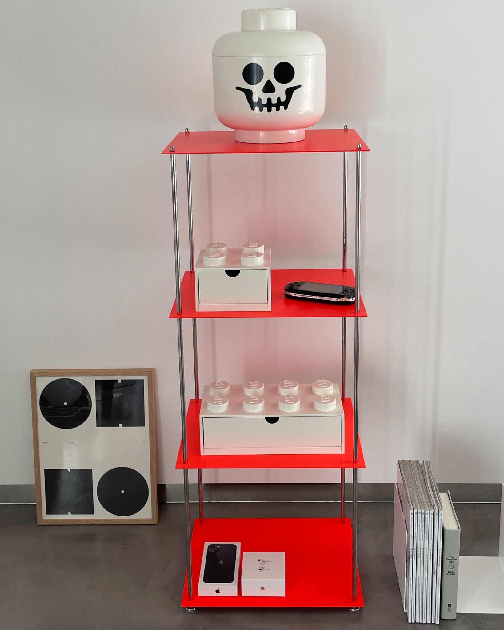 Leuchtrotes Regal mit weißem Lego-Kopf, Konsole und Designobjekten im Wohnzimmer