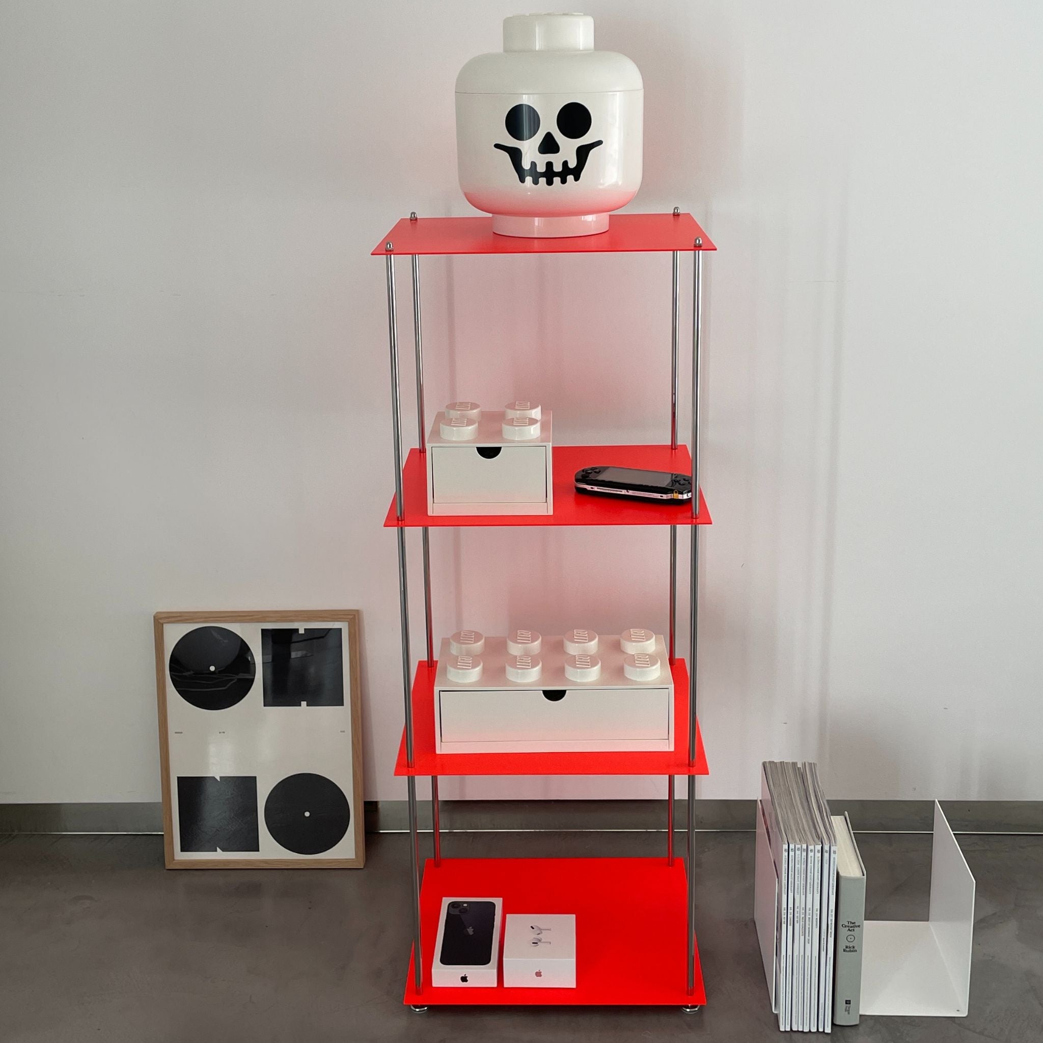 Leuchtrotes Regal mit weißem Lego-Kopf, Konsole und Designobjekten im Wohnzimmer