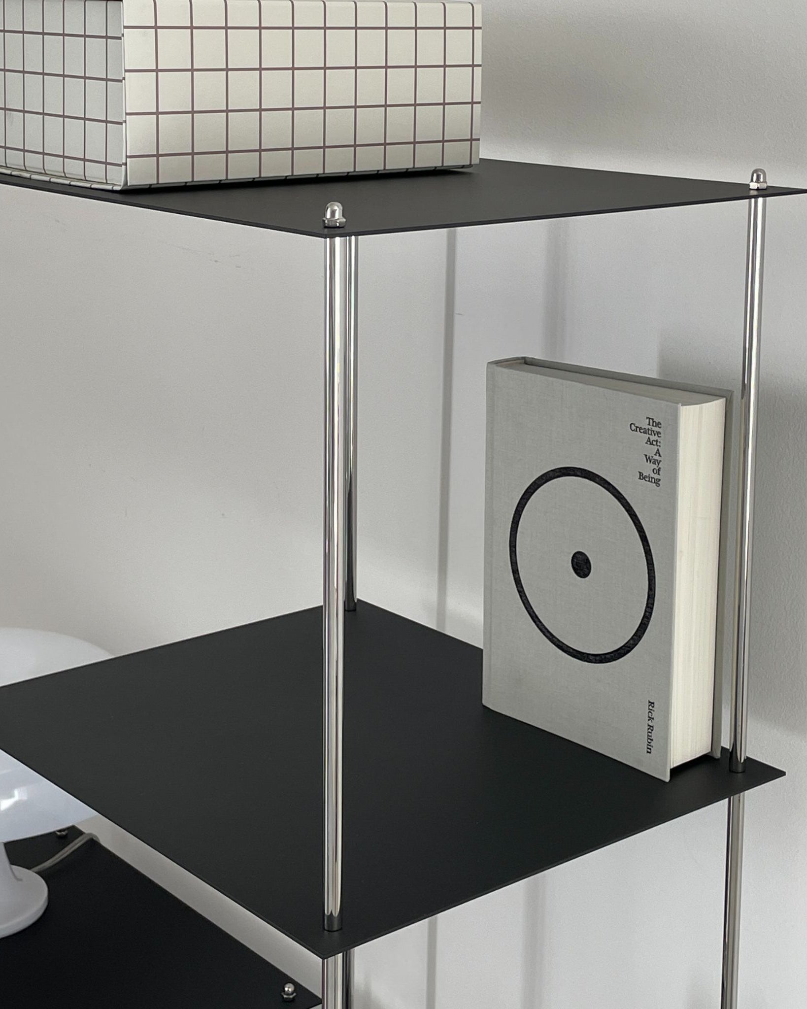 Detailansicht eines schwarzen Designregals von MO INTERIORS mit grafischer Box und Buch im minimalistischen Interieur