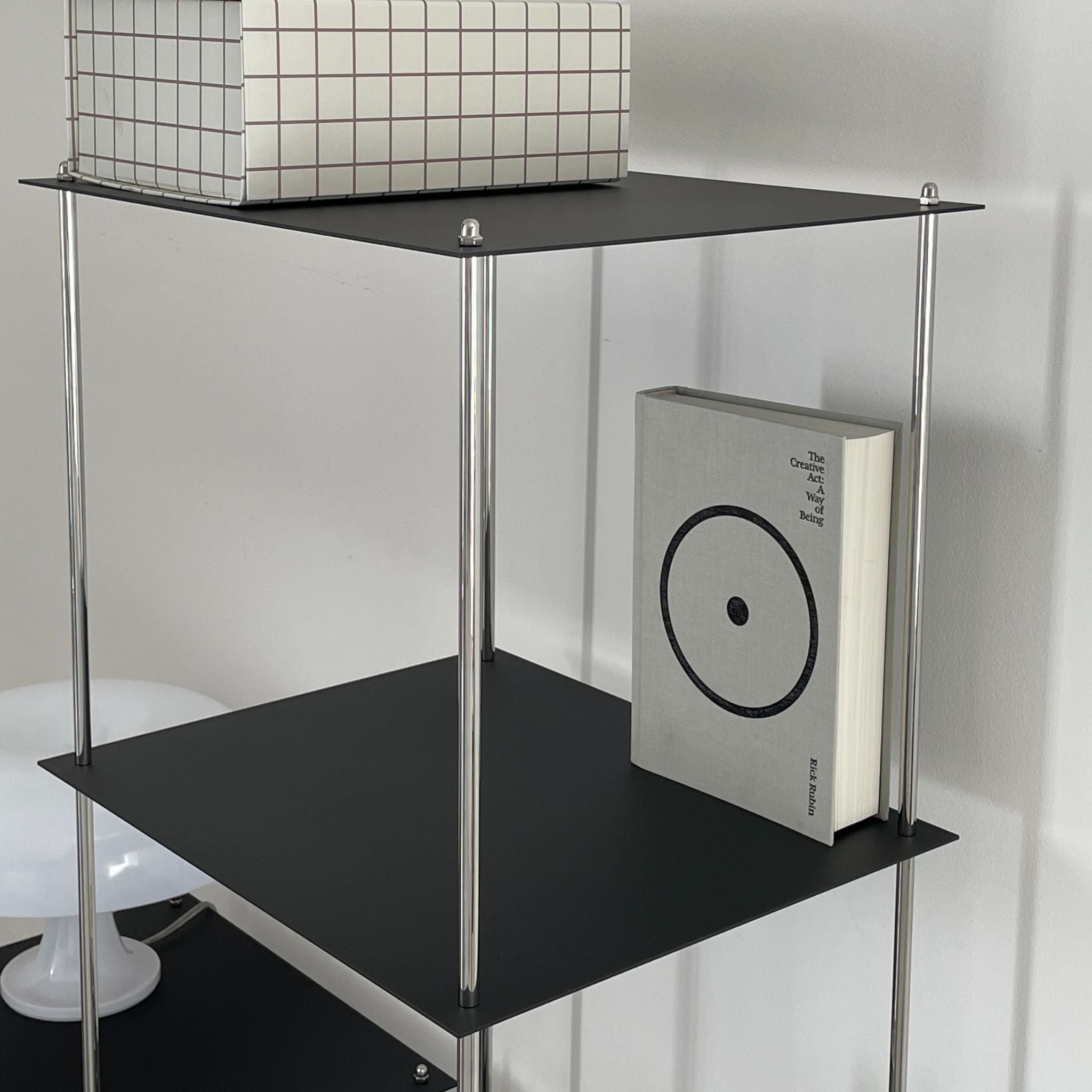 Detailansicht eines schwarzen Designregals von MO INTERIORS mit grafischer Box und Buch im minimalistischen Interieur