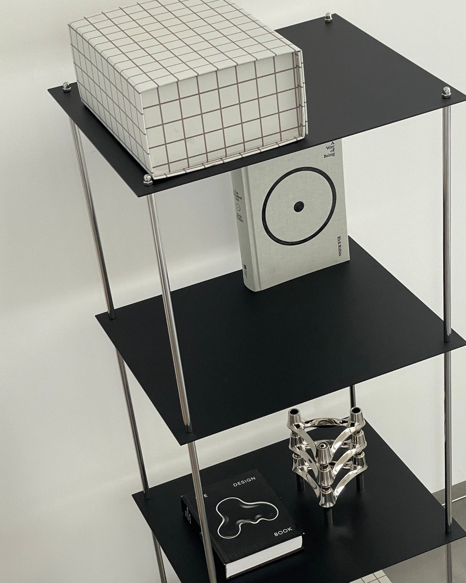 Modernes schwarzes Regal von MO INTERIORS mit Designbuch, Kerzenhalter und Rasterbox in minimalistischem Interieur