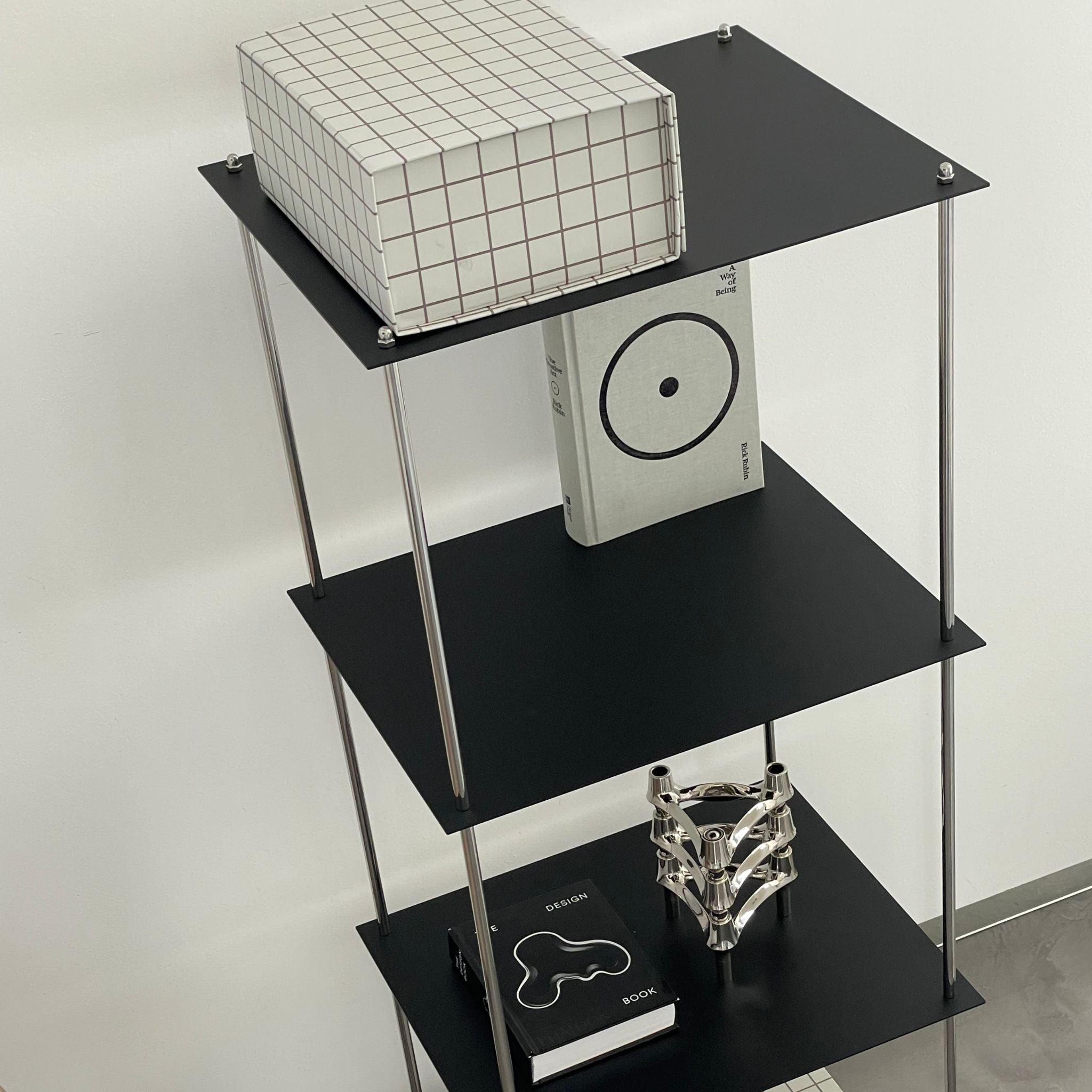 Modernes schwarzes Regal von MO INTERIORS mit Designbuch, Kerzenhalter und Rasterbox in minimalistischem Interieur