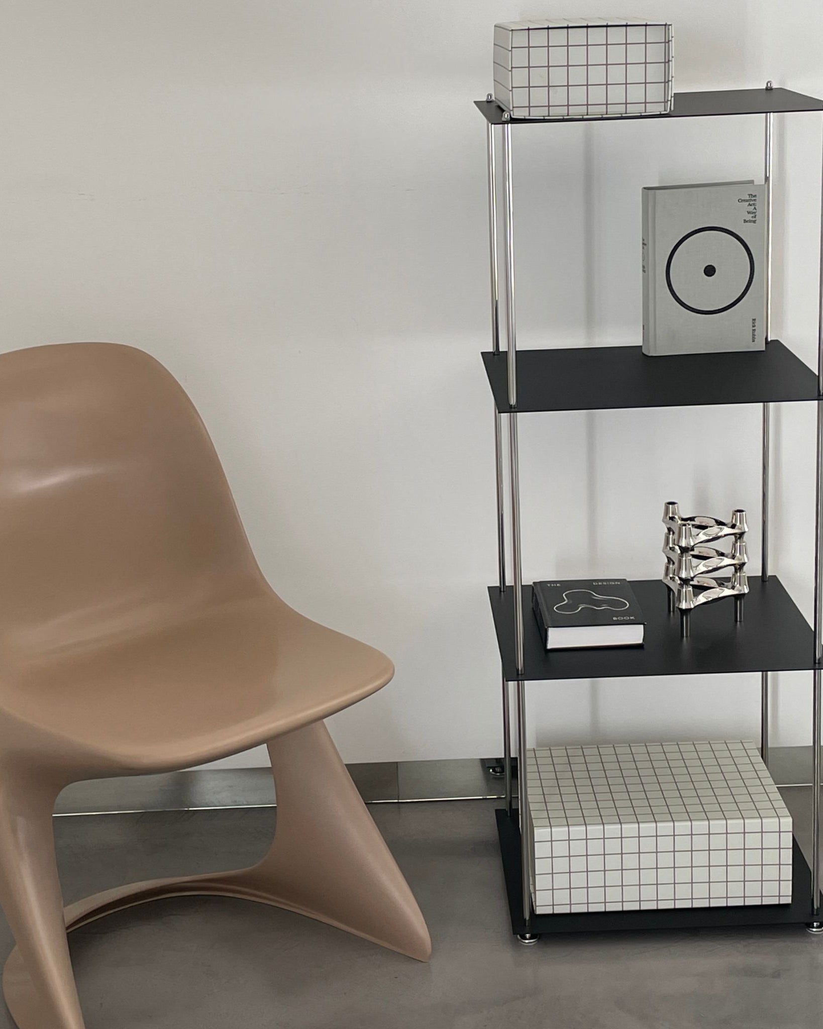 Modernes schwarzes Regal von MO INTERIORS mit Designobjekten und beigem Stuhl in puristischem Wohnraum