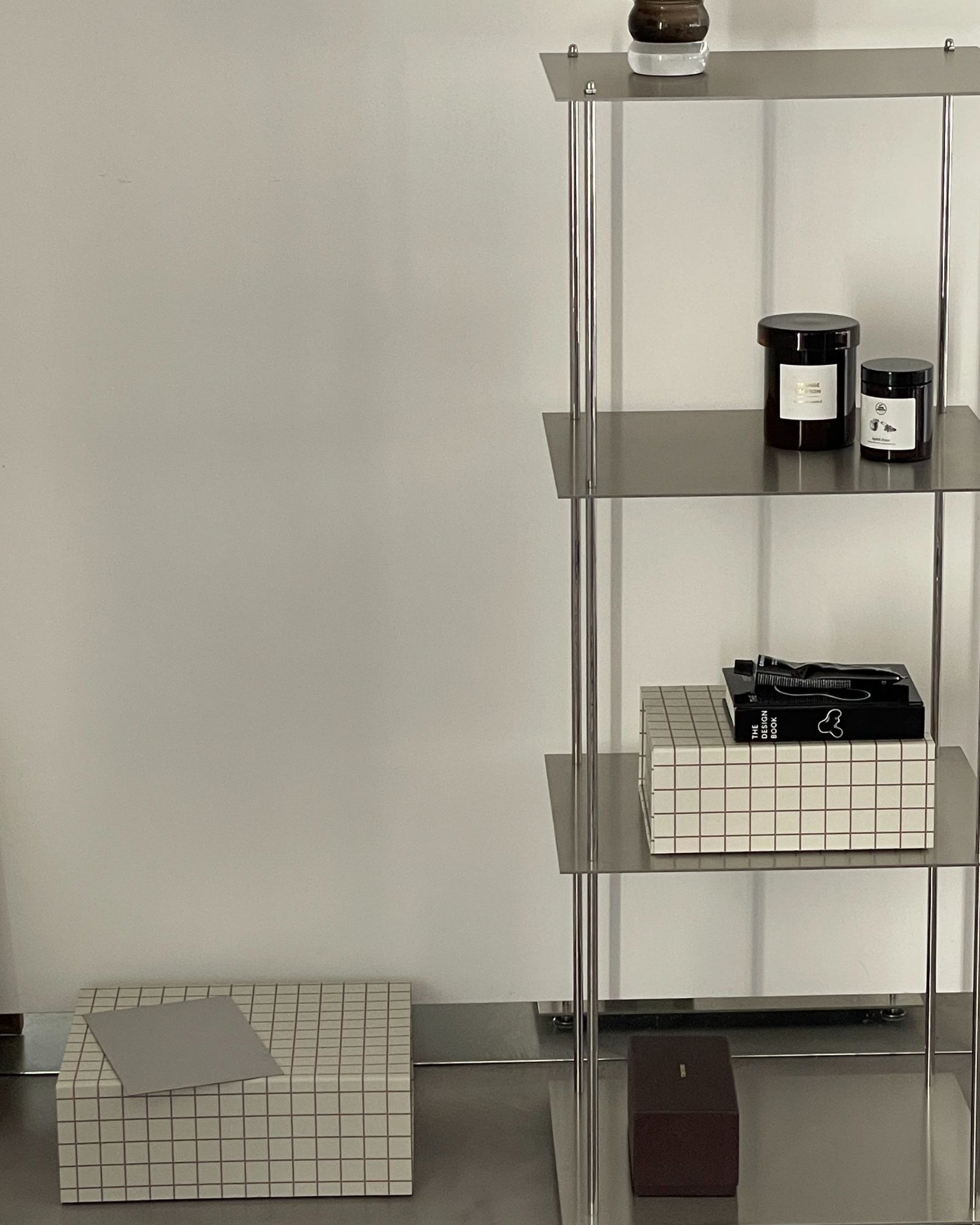 Modulares Regal aus Edelstahl mit Duftkerzen, Büchern und Boxen im minimalistischen Stil