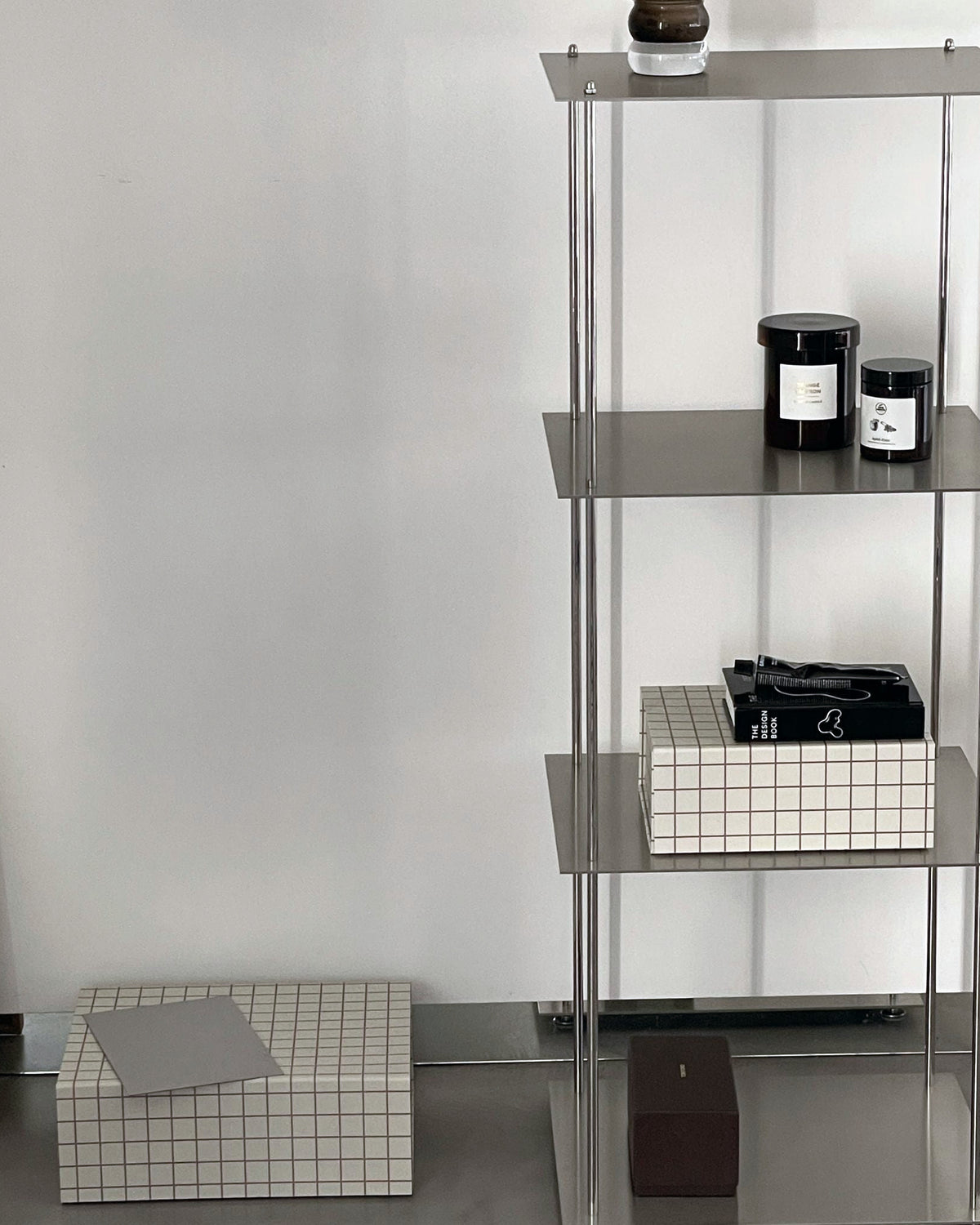 Modulares Regal aus Edelstahl mit Duftkerzen, Büchern und Boxen im minimalistischen Stil