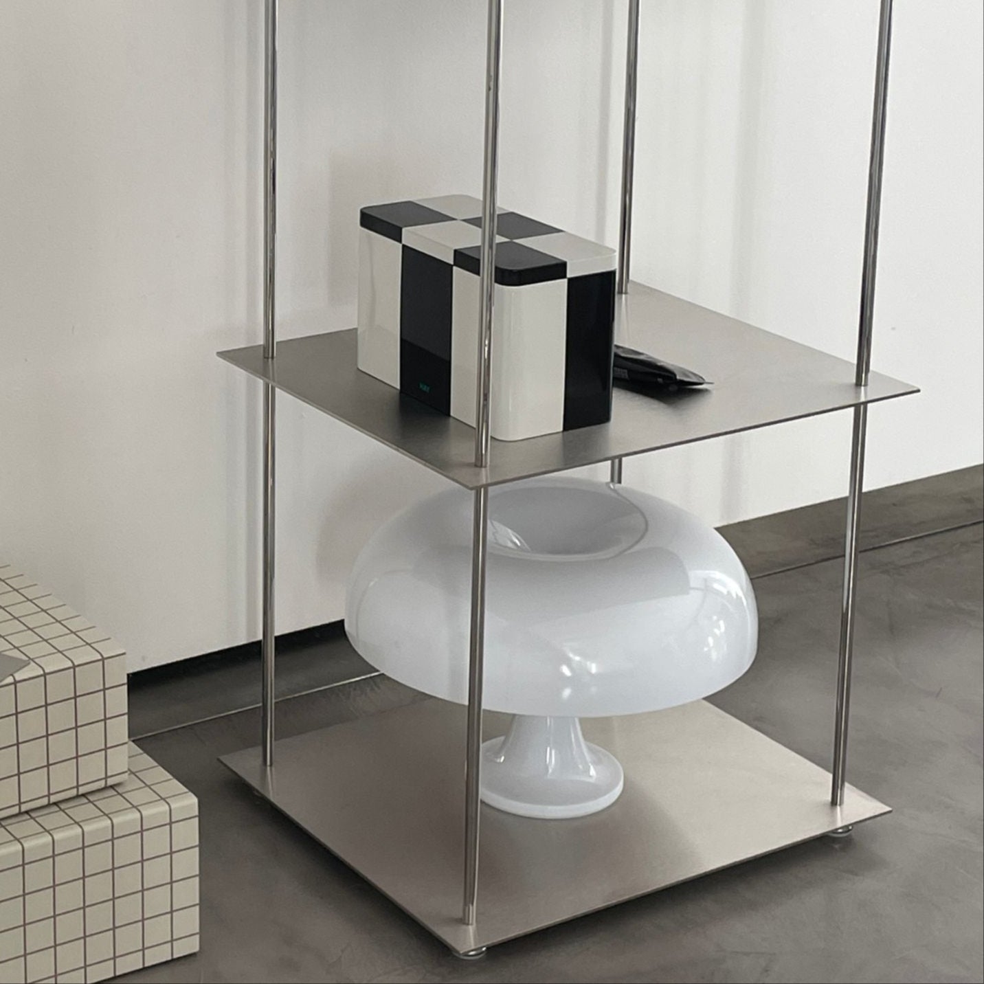 Modernes Edelstahl-Regal mit grafischem Kunstwerk, Designobjekten und Aufbewahrungsboxen