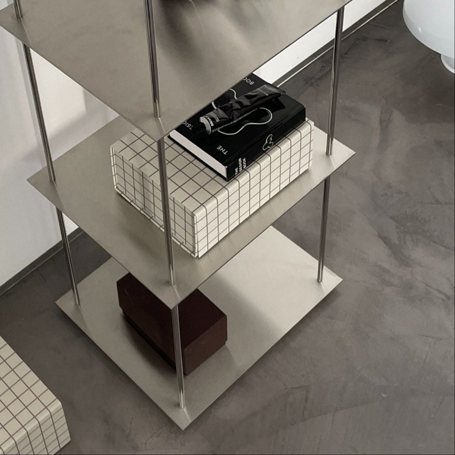 Minimalistisches Edelstahl-Regal mit geometrischen Boxen und Duftkerzen