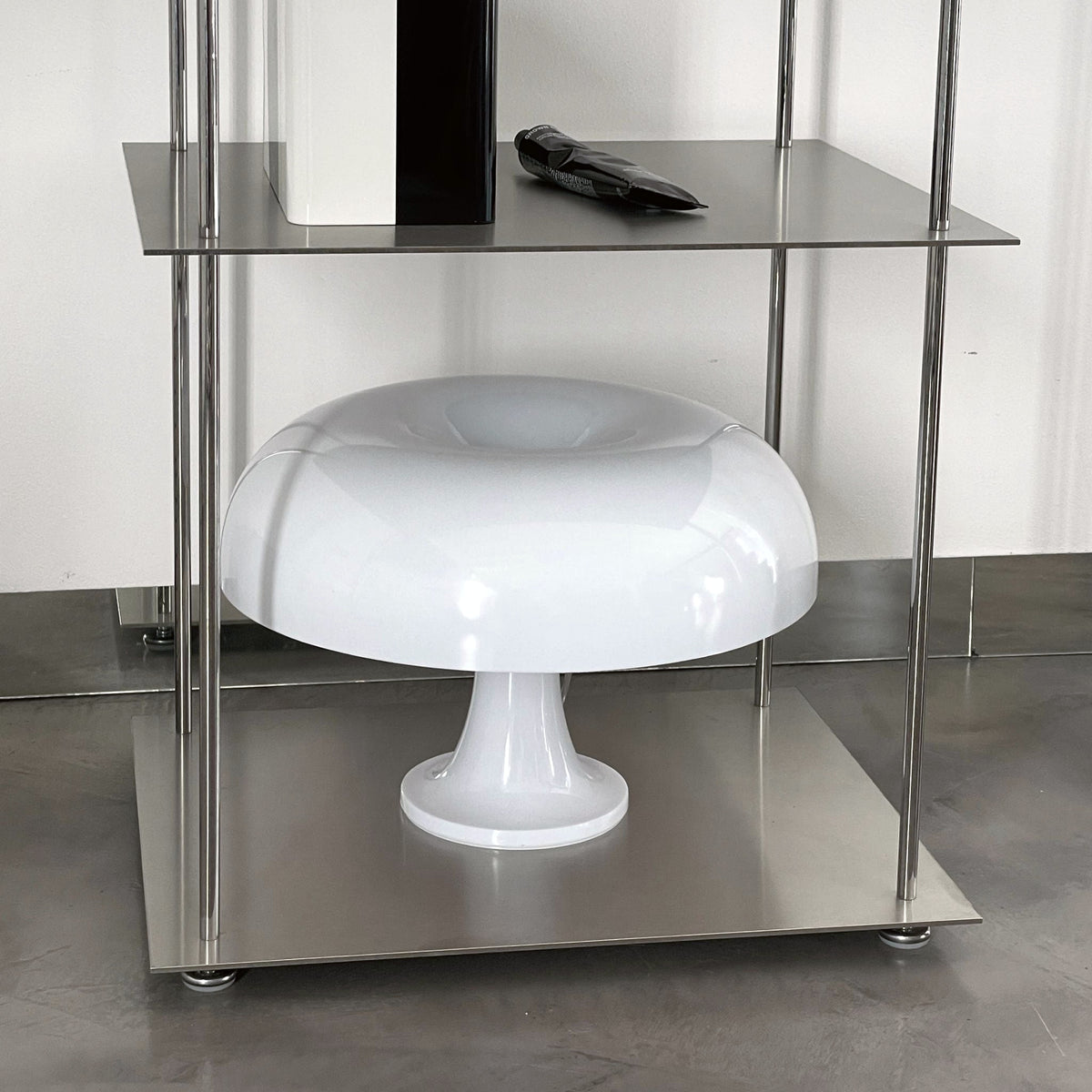 Detailansicht eines modularen Edelstahl-Regals mit Designerlampe und stilvollen Accessoires