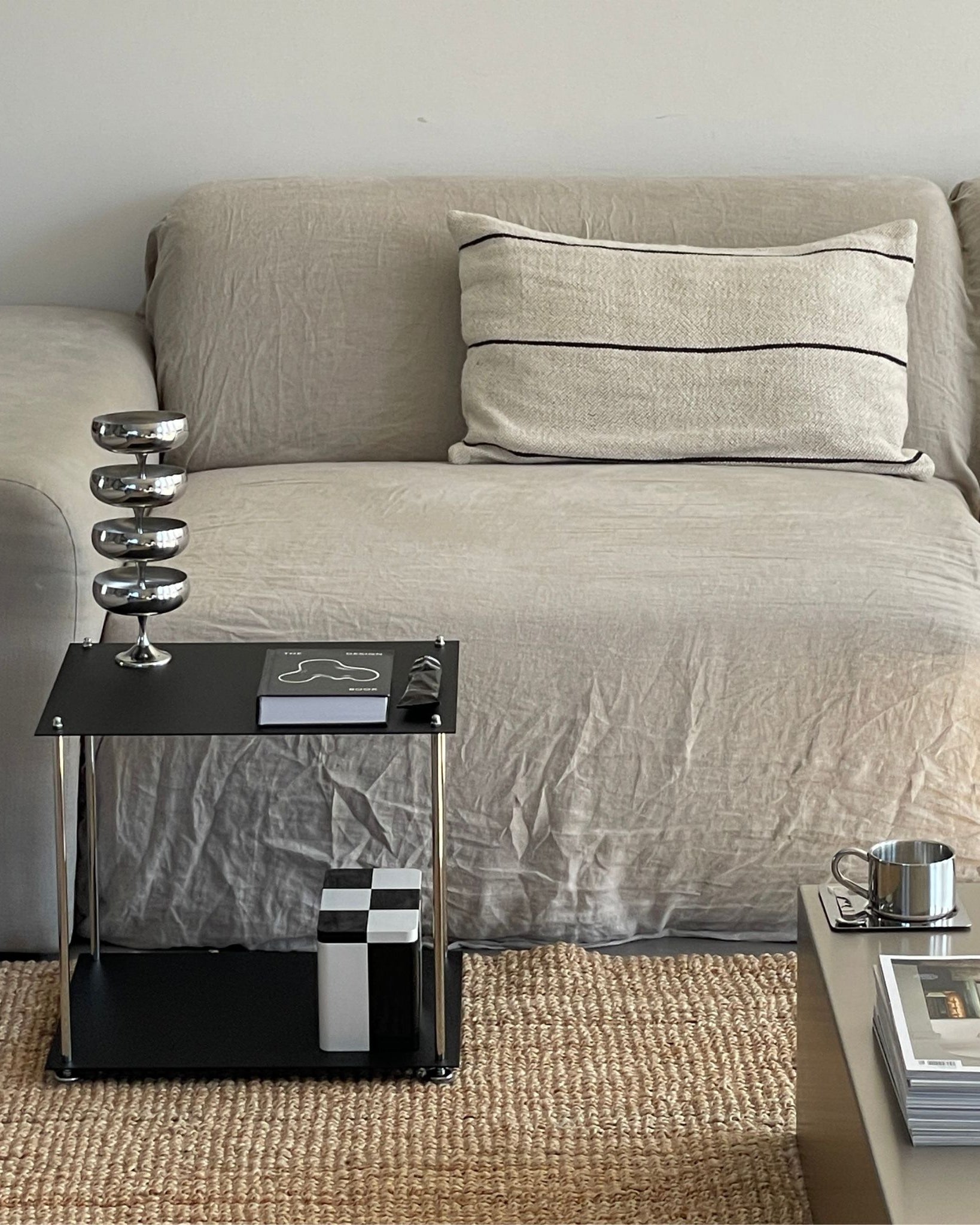 Schwarzes MODULUM Regal mit Pulverbeschichtung als stilvoller Beistelltisch neben beigem Sofa im Wohnzimmer