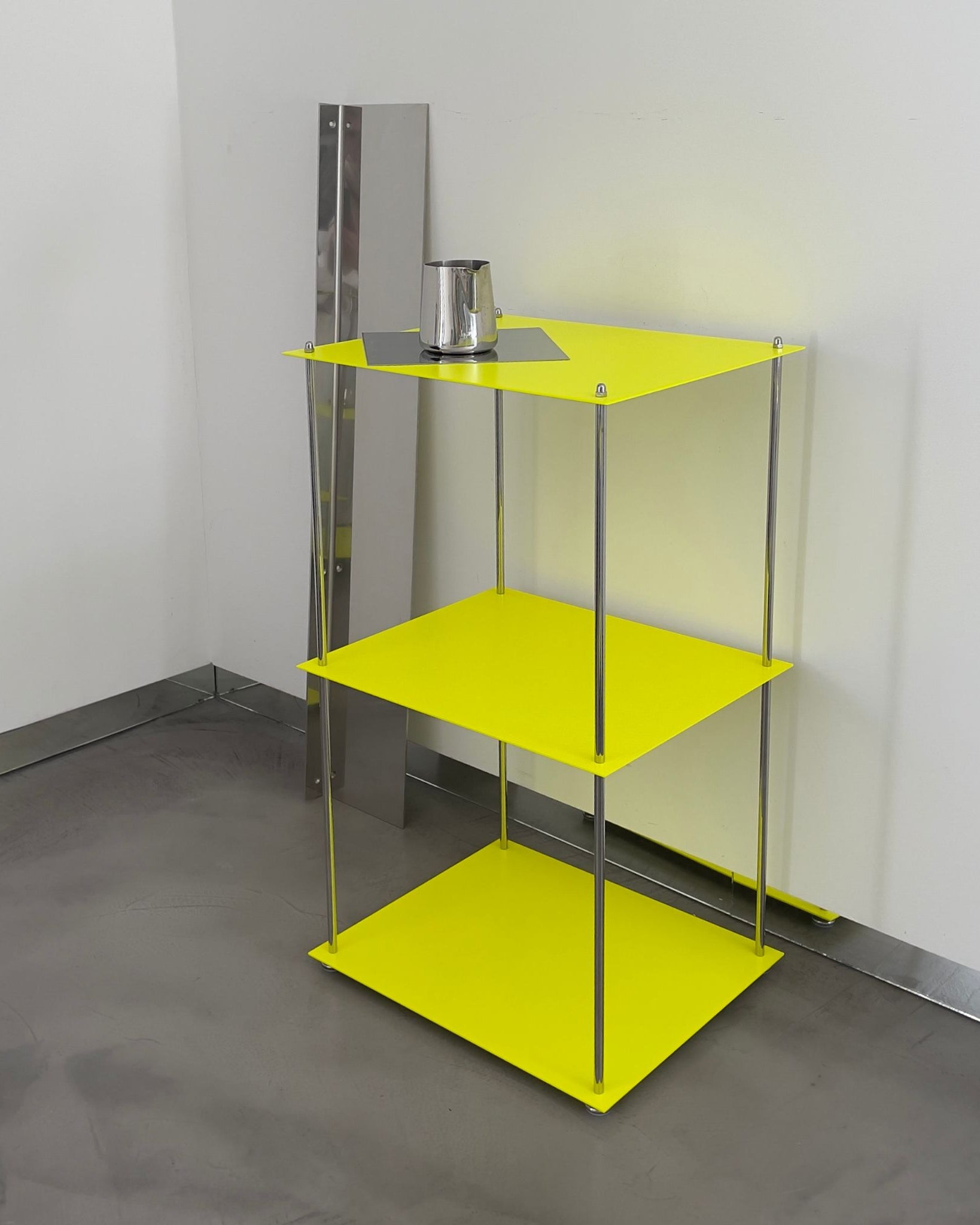 MODULUM Regal in Leuchtgelb mit Edelstahlstreben und Spiegelplatte, seitlich fotografiert in moderner Raumszene