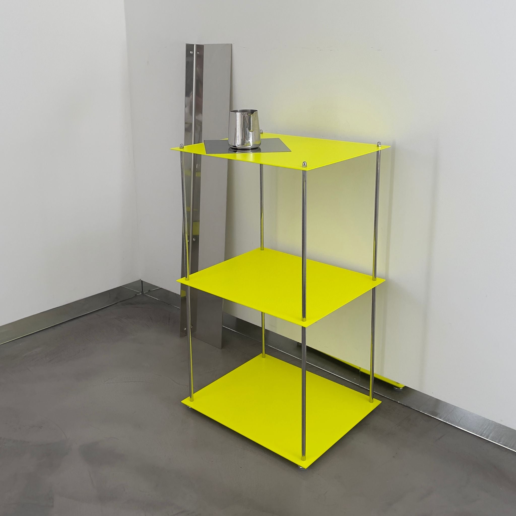 MODULUM Regal in Leuchtgelb mit Edelstahlstreben und Spiegelplatte, seitlich fotografiert in moderner Raumszene