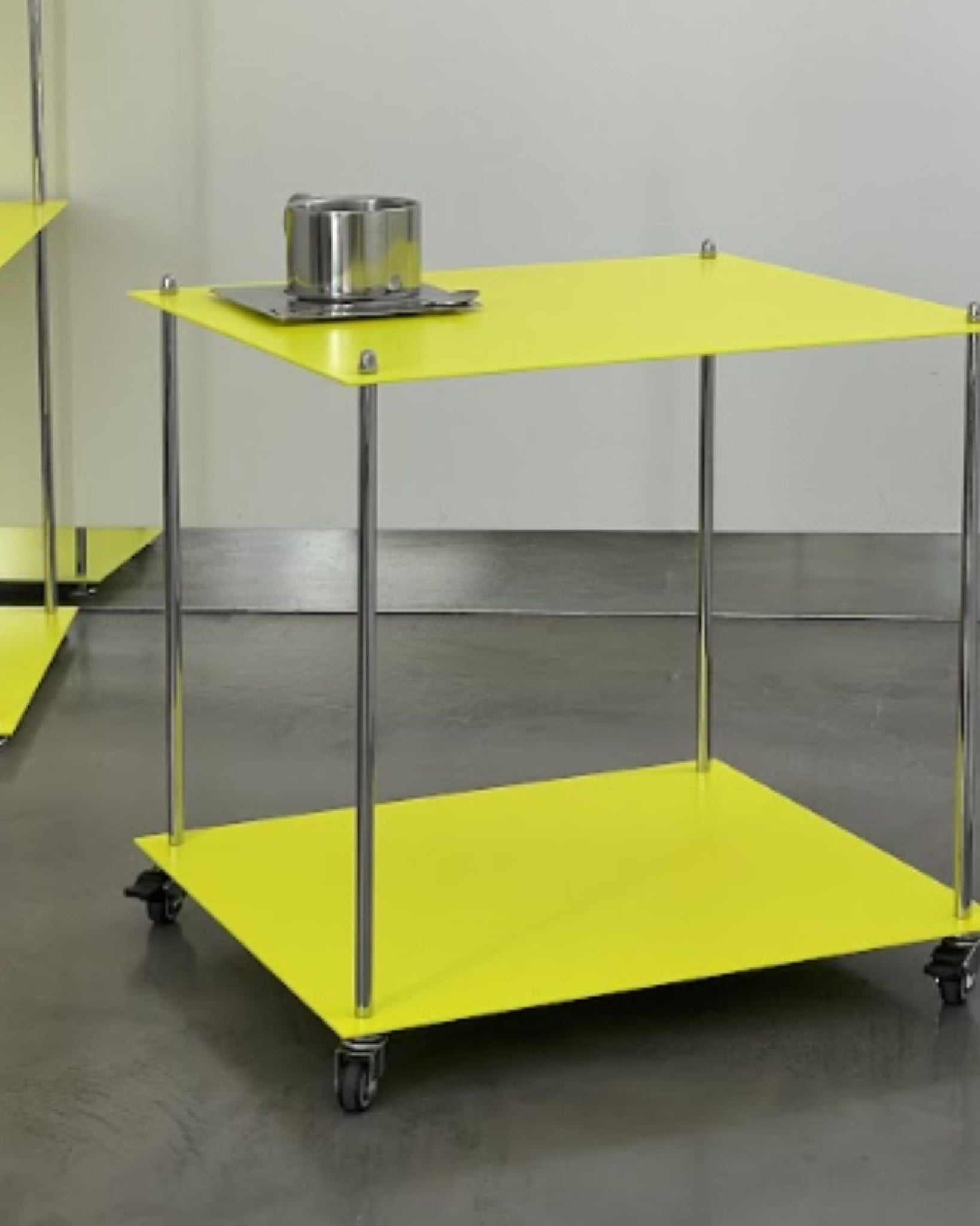 Leuchtgelbes Regalmodul Modulum mit Rollen und Edelstahlstreben, seitliche Perspektive auf grauem Betonboden