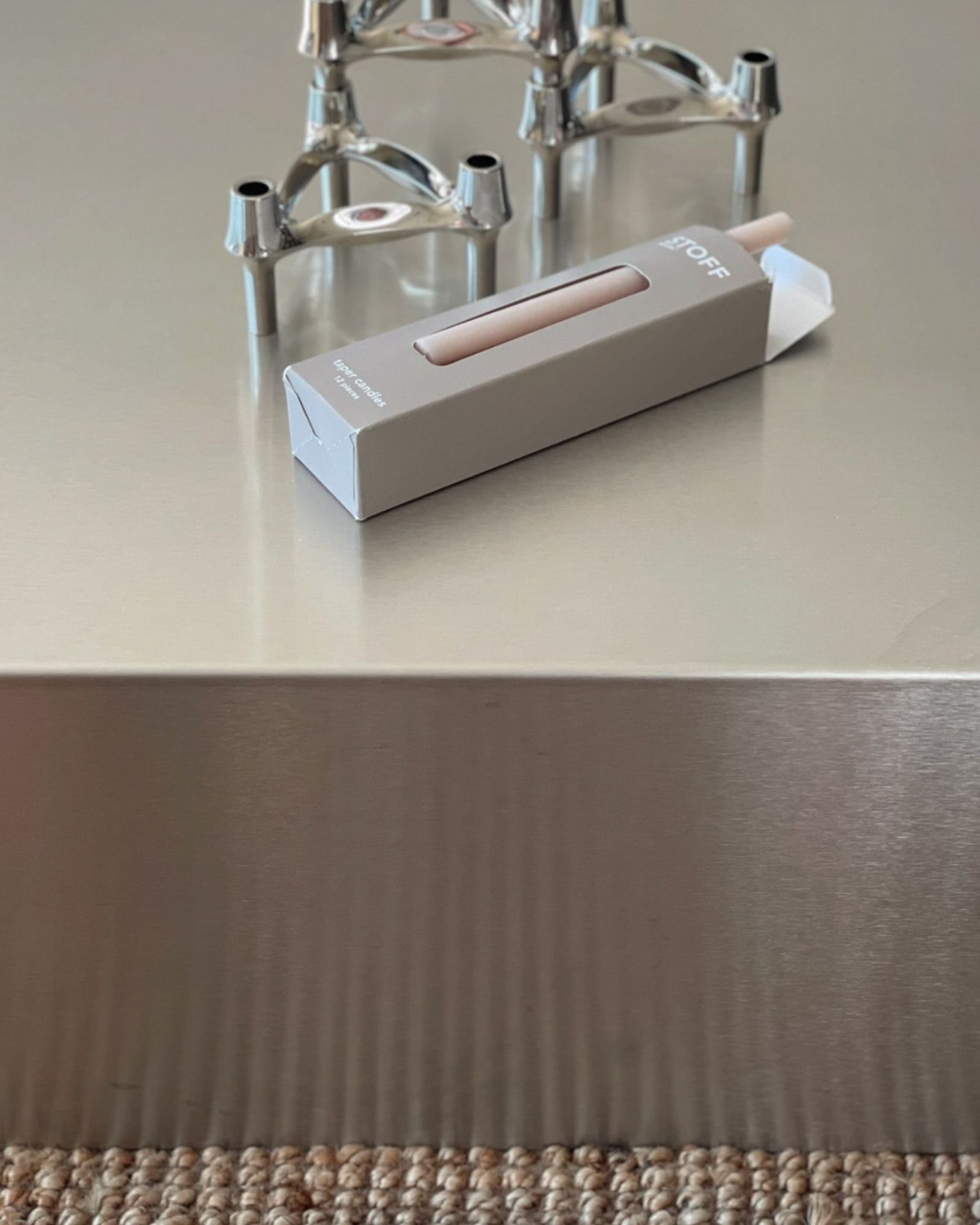 Detailaufnahme eines Couchtisches aus gebürstetem Edelstahl mit stilvoller Dekoration und minimalistischem Design