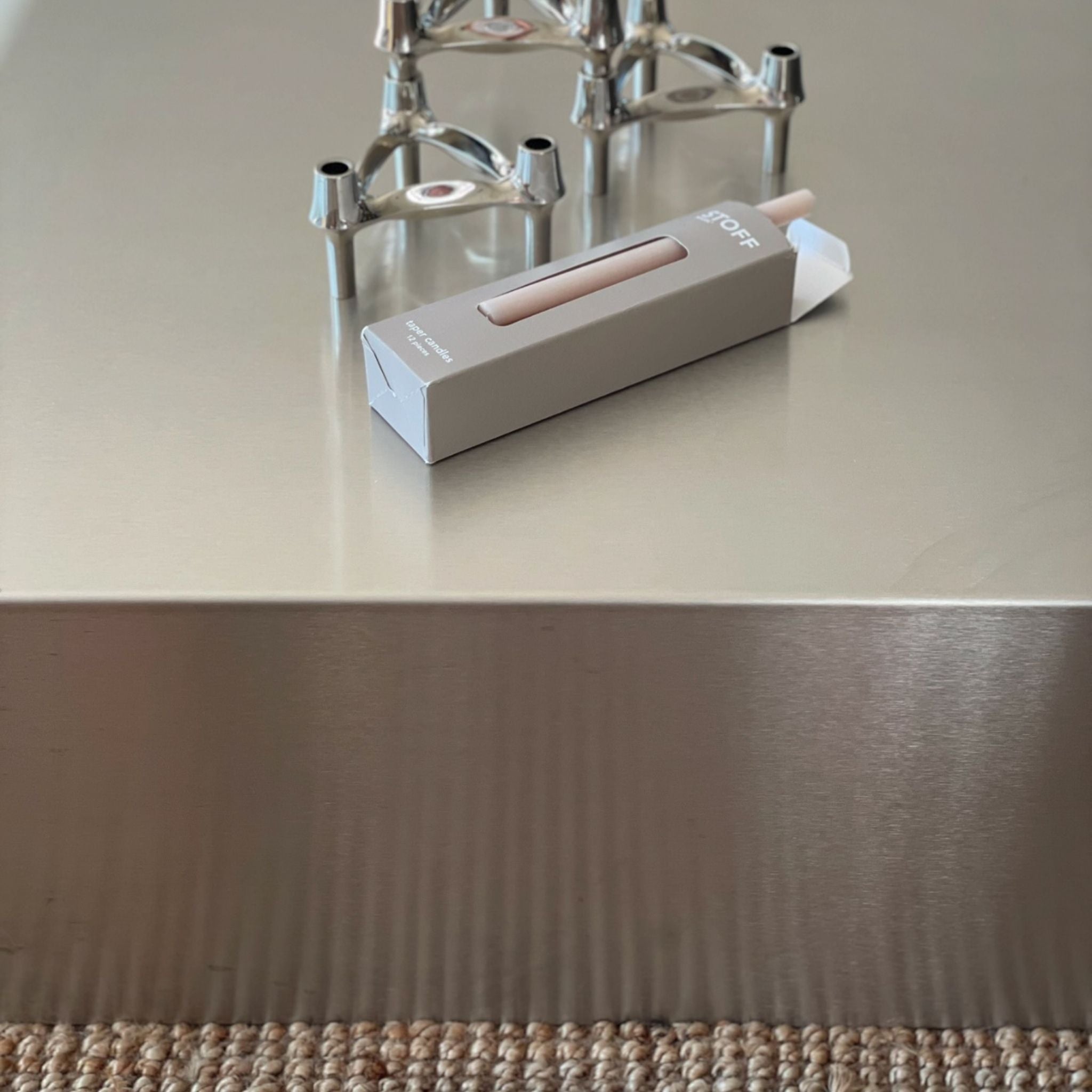 Detailaufnahme eines Couchtisches aus gebürstetem Edelstahl mit stilvoller Dekoration und minimalistischem Design