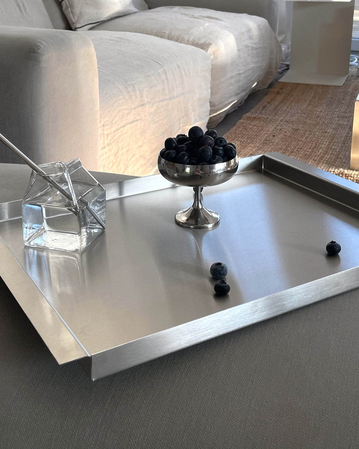 modernes edelstahl tablett ray auf sofa mit blaubeeren im wohnzimmer