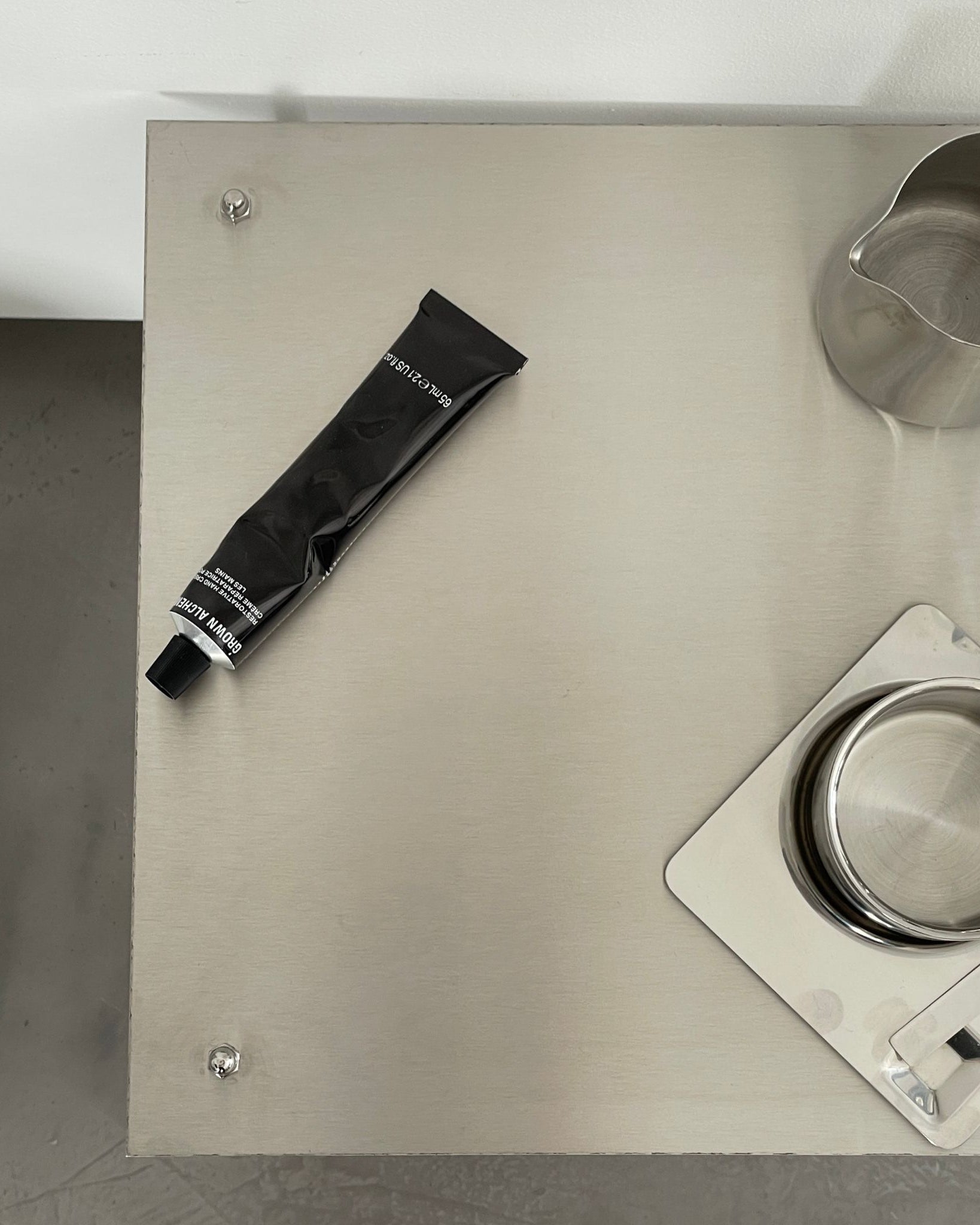 Detailansicht eines modularen Regalsystems aus gebürstetem Edelstahl mit Tasse, Tablett und Designobjekten