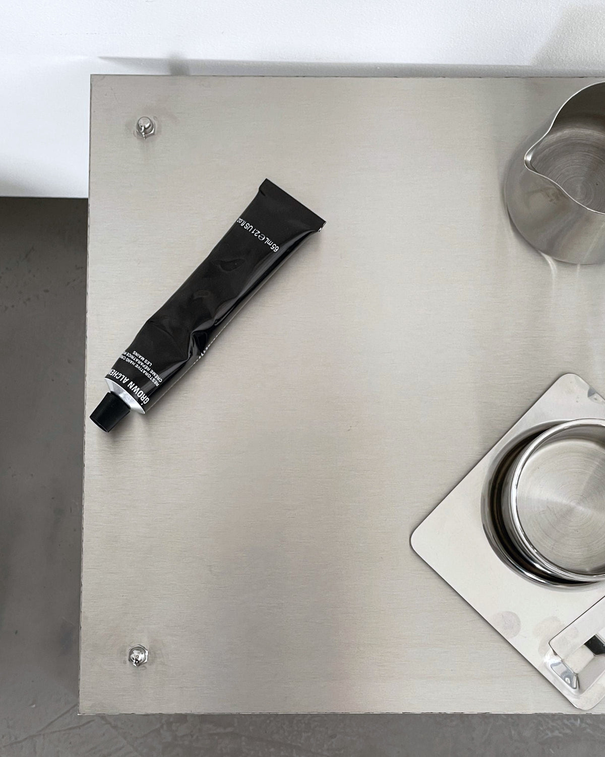 Detailansicht eines modularen Regalsystems aus gebürstetem Edelstahl mit Tasse, Tablett und Designobjekten