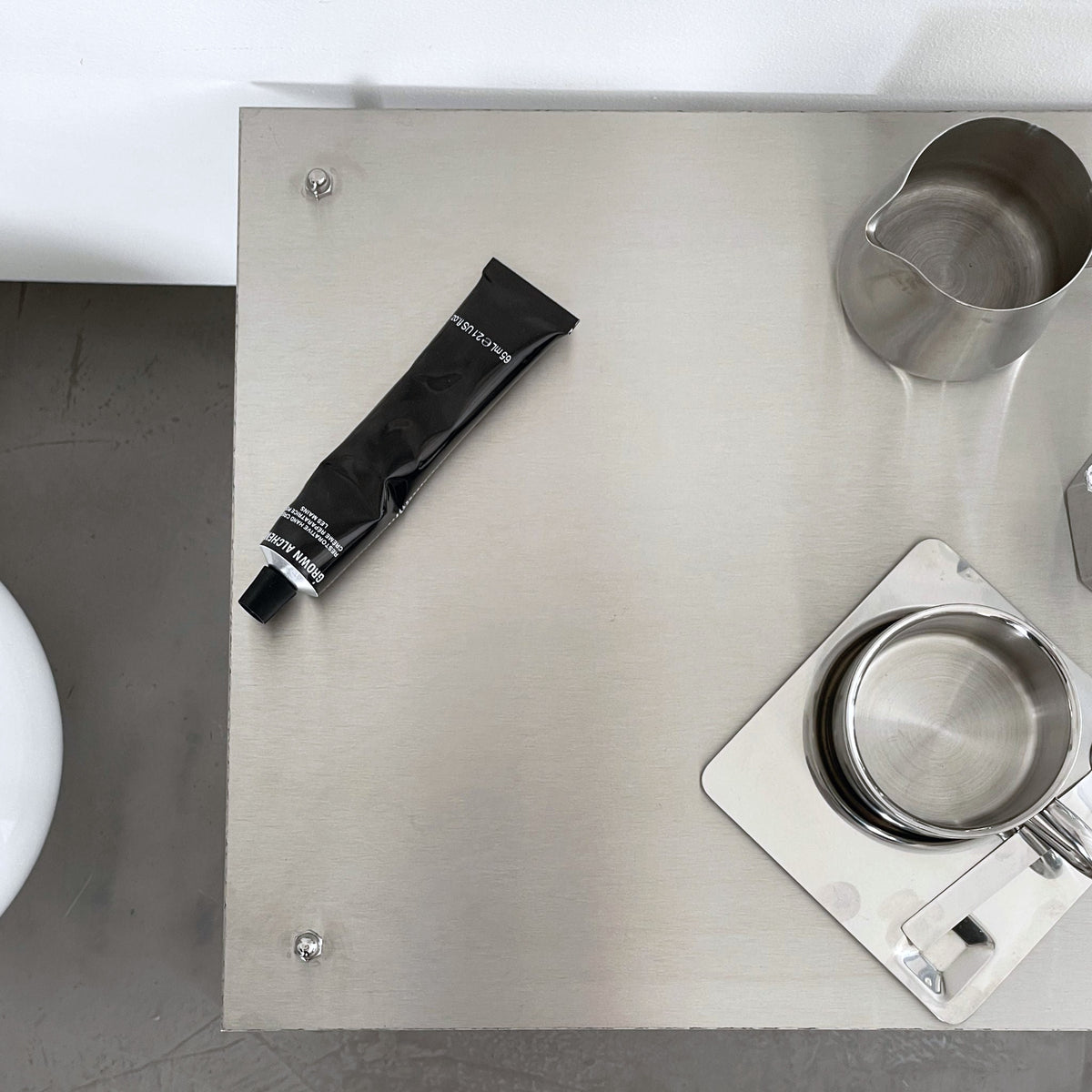 Detailansicht eines modularen Regalsystems aus gebürstetem Edelstahl mit Tasse, Tablett und Designobjekten