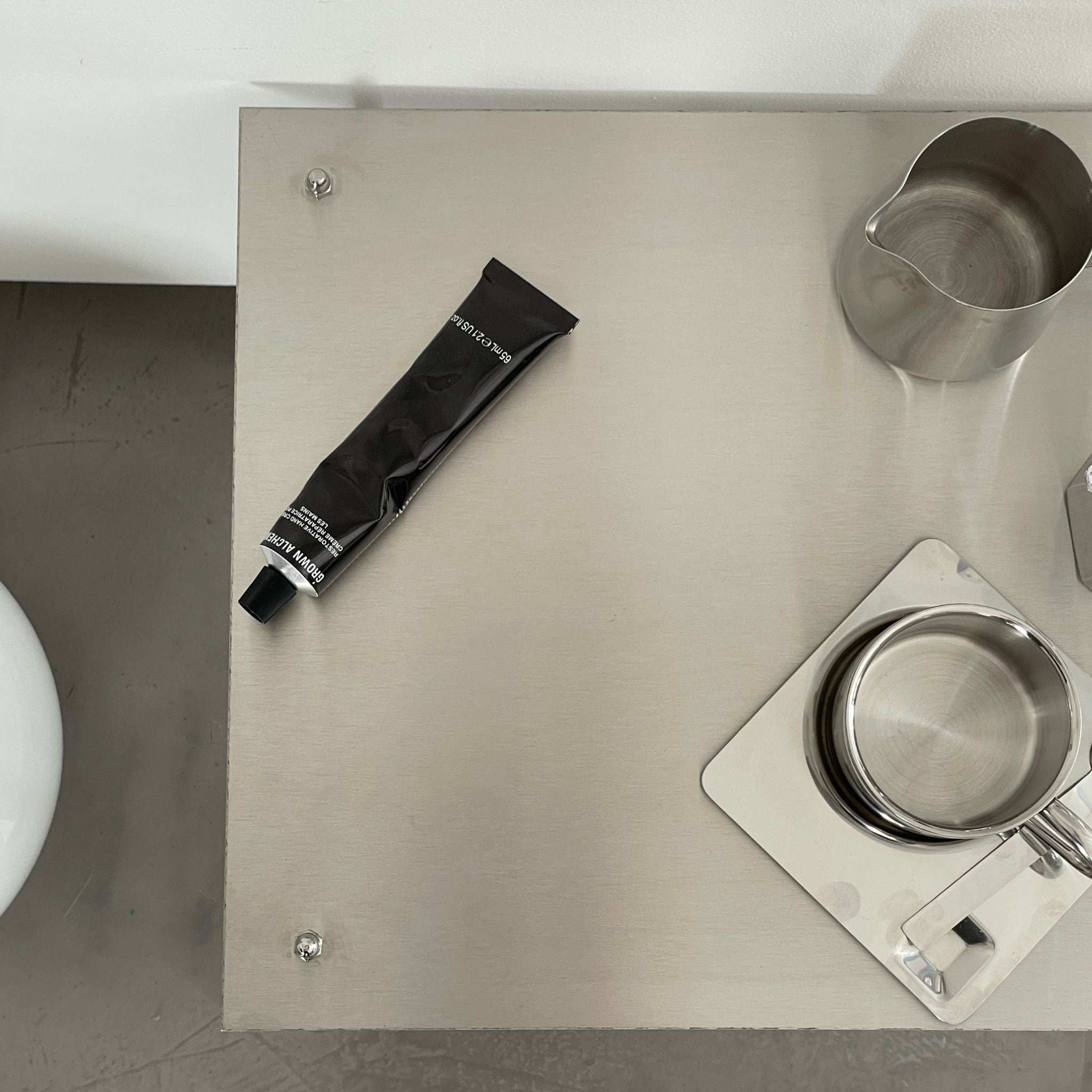 Detailansicht eines modularen Regalsystems aus gebürstetem Edelstahl mit Tasse, Tablett und Designobjekten