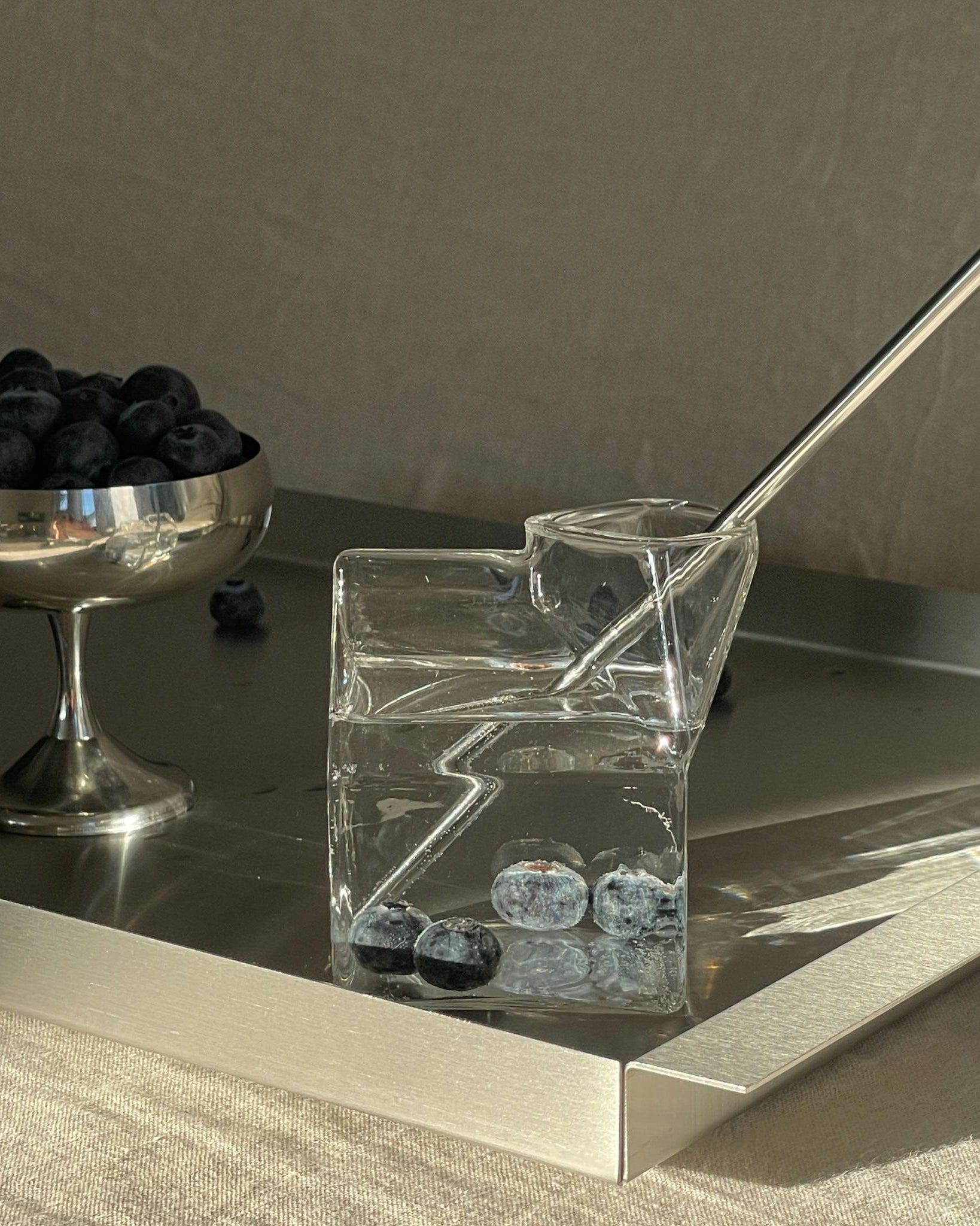 edelstahl tablett mit milchkarton glas und blaubeeren im morgenlicht